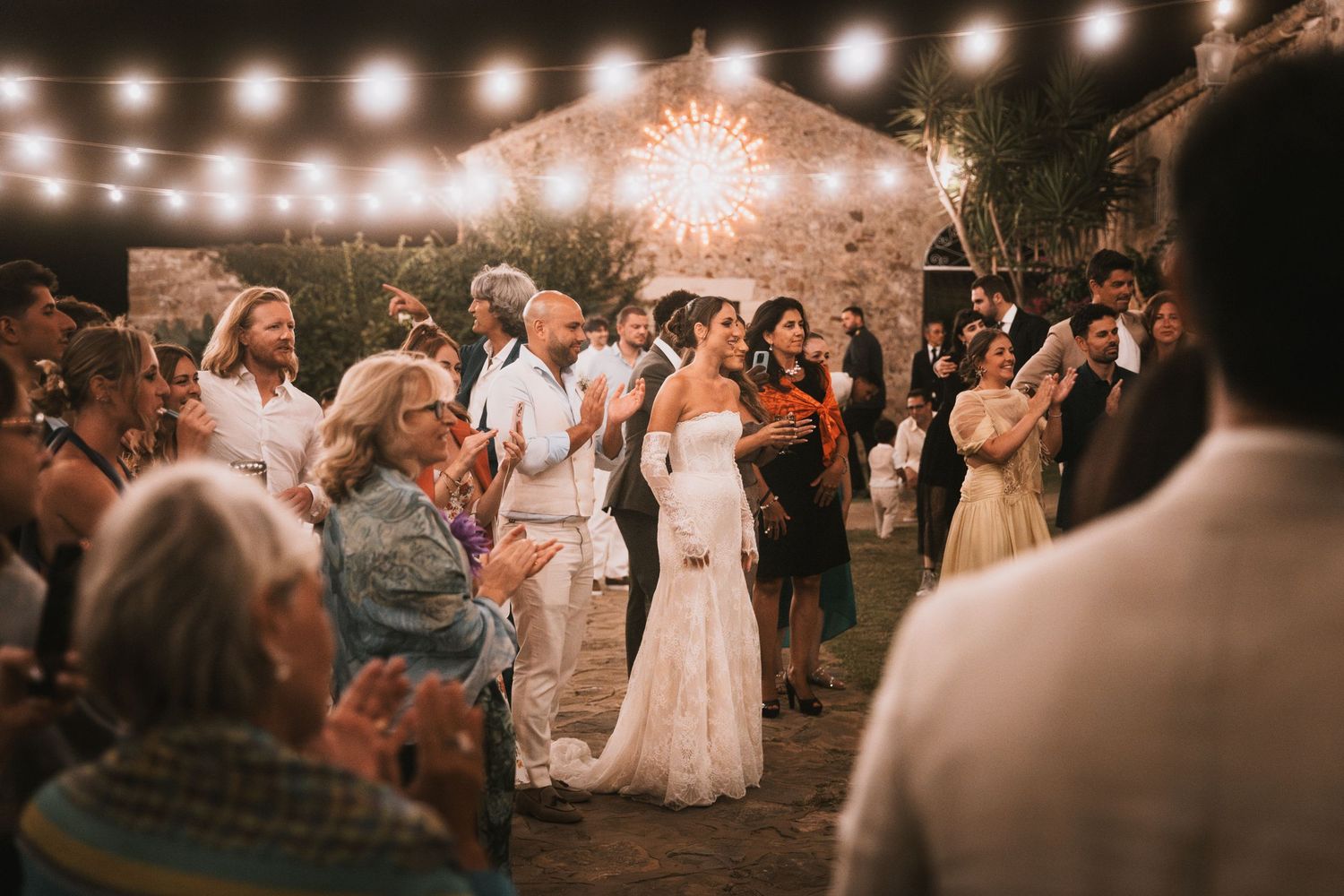 Nighttime wedding celebration with string lights and dancing guests.