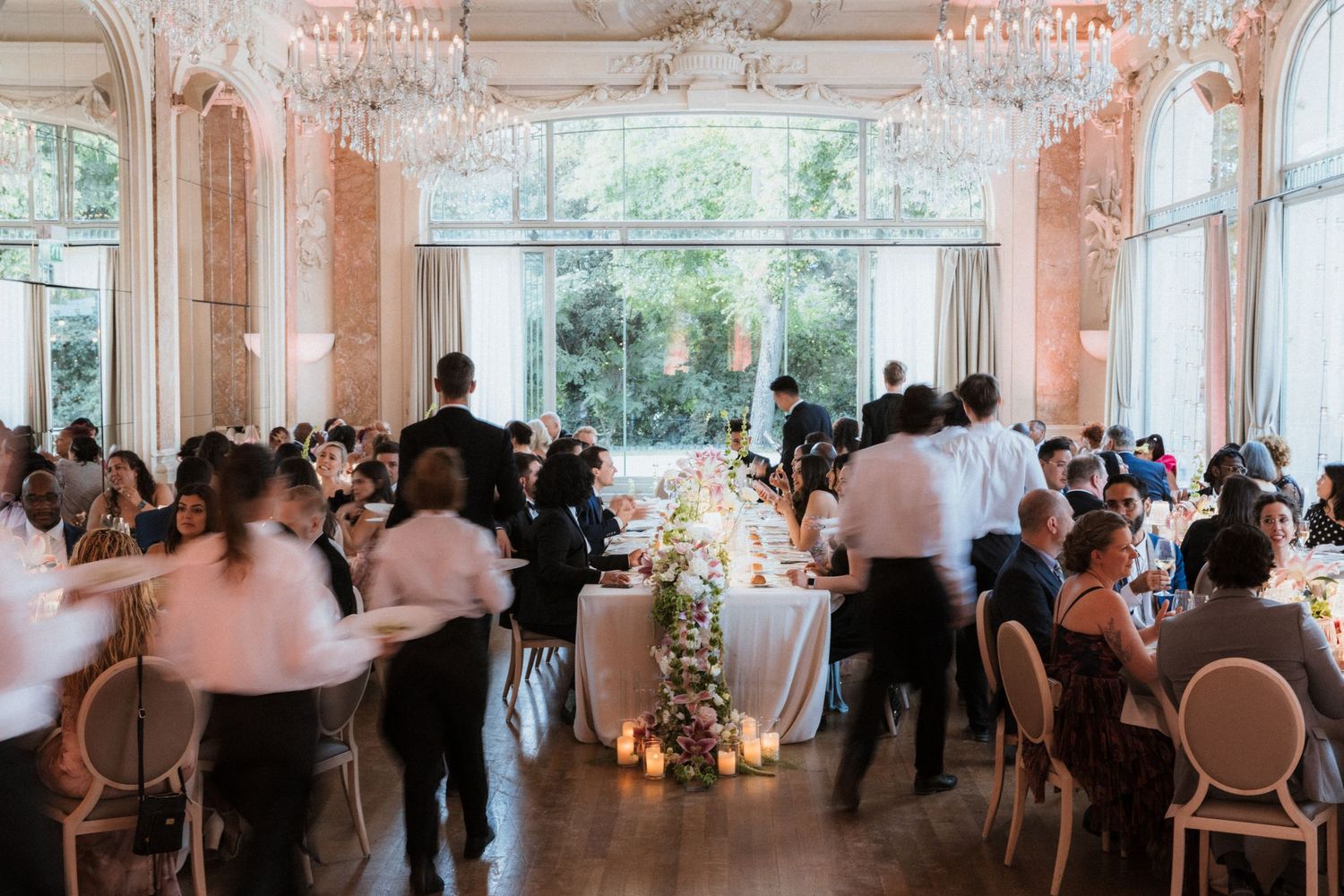 Elegant ballroom reception venue with crystal chandeliers and large windows.