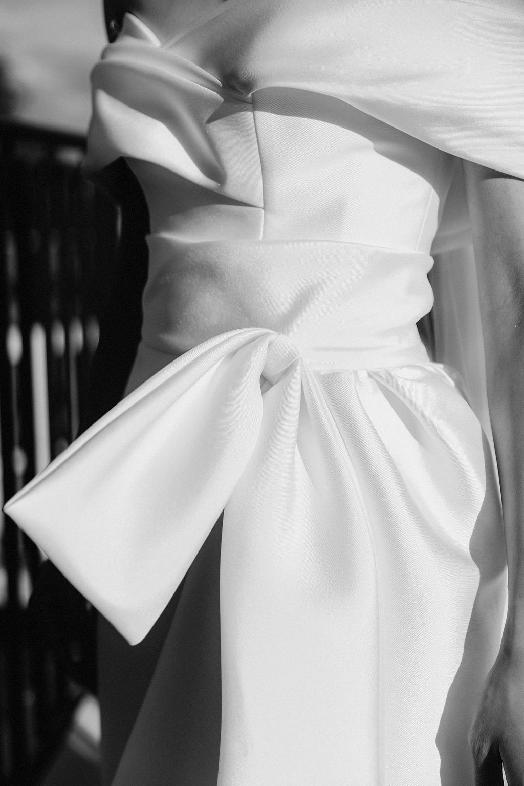 Close-up details of an elegant white wedding dress with architectural bow elements.