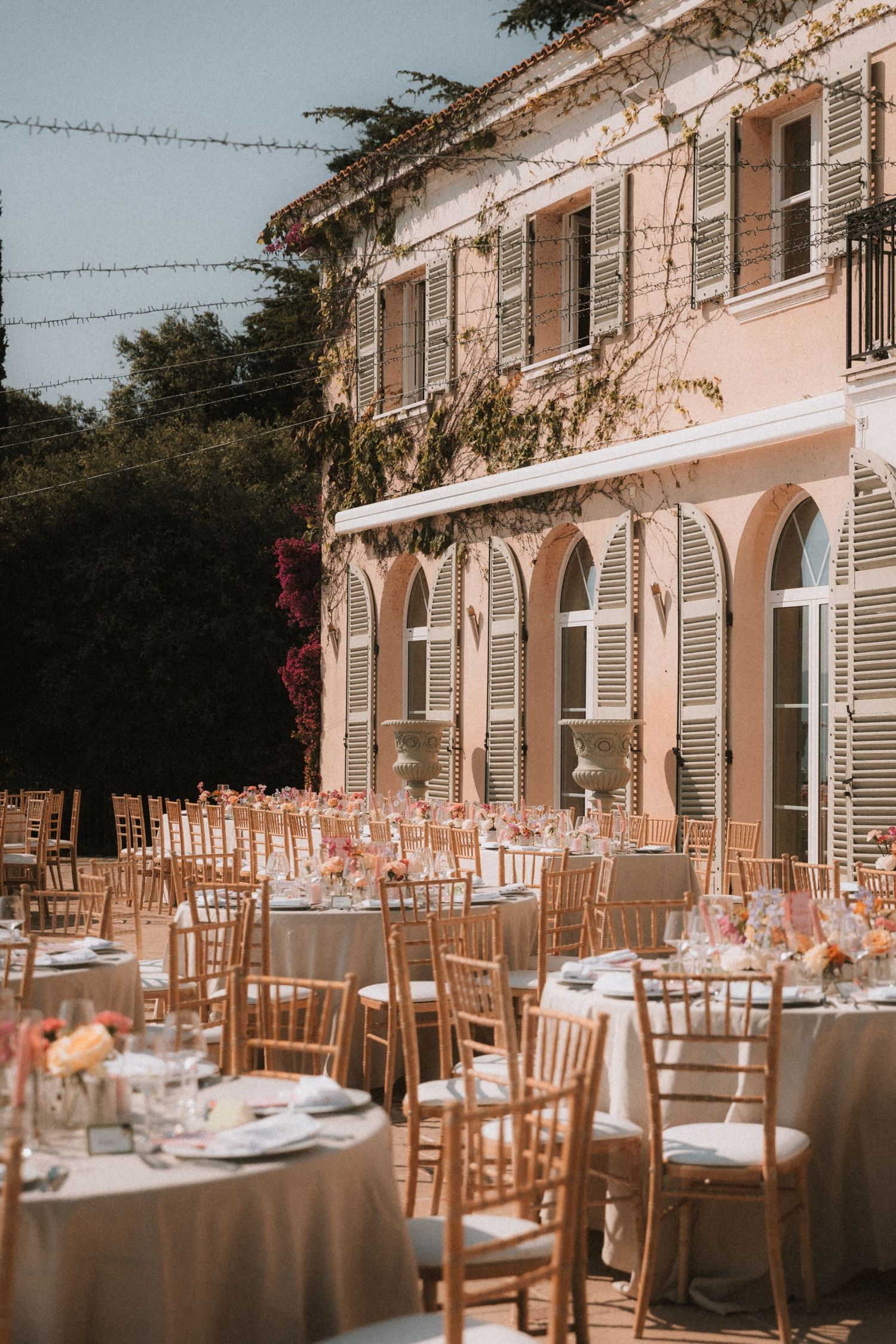 Elegant outdoor wedding reception venue with tables set against a Mediterranean-style building.