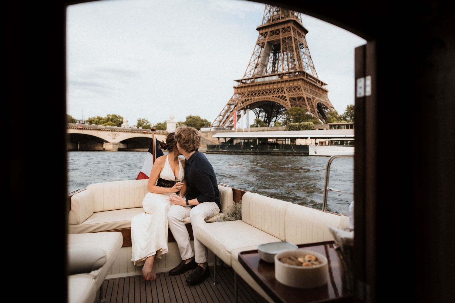 Couple sharing a romantic moment on a luxury boat on the Seine River with the Eiffel Tower in Paris backdrop.