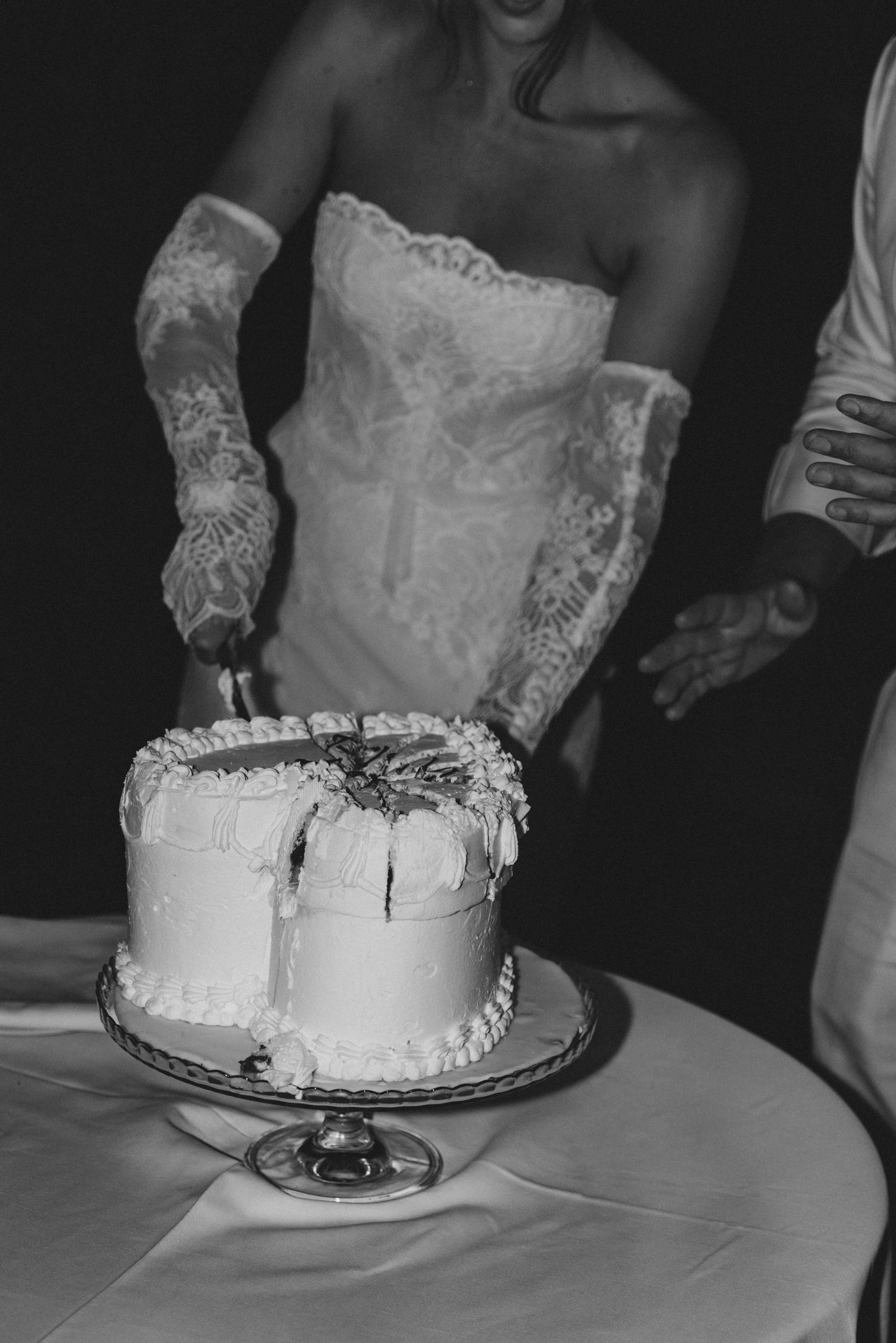 Close-up of a white wedding cake being cut during the reception.