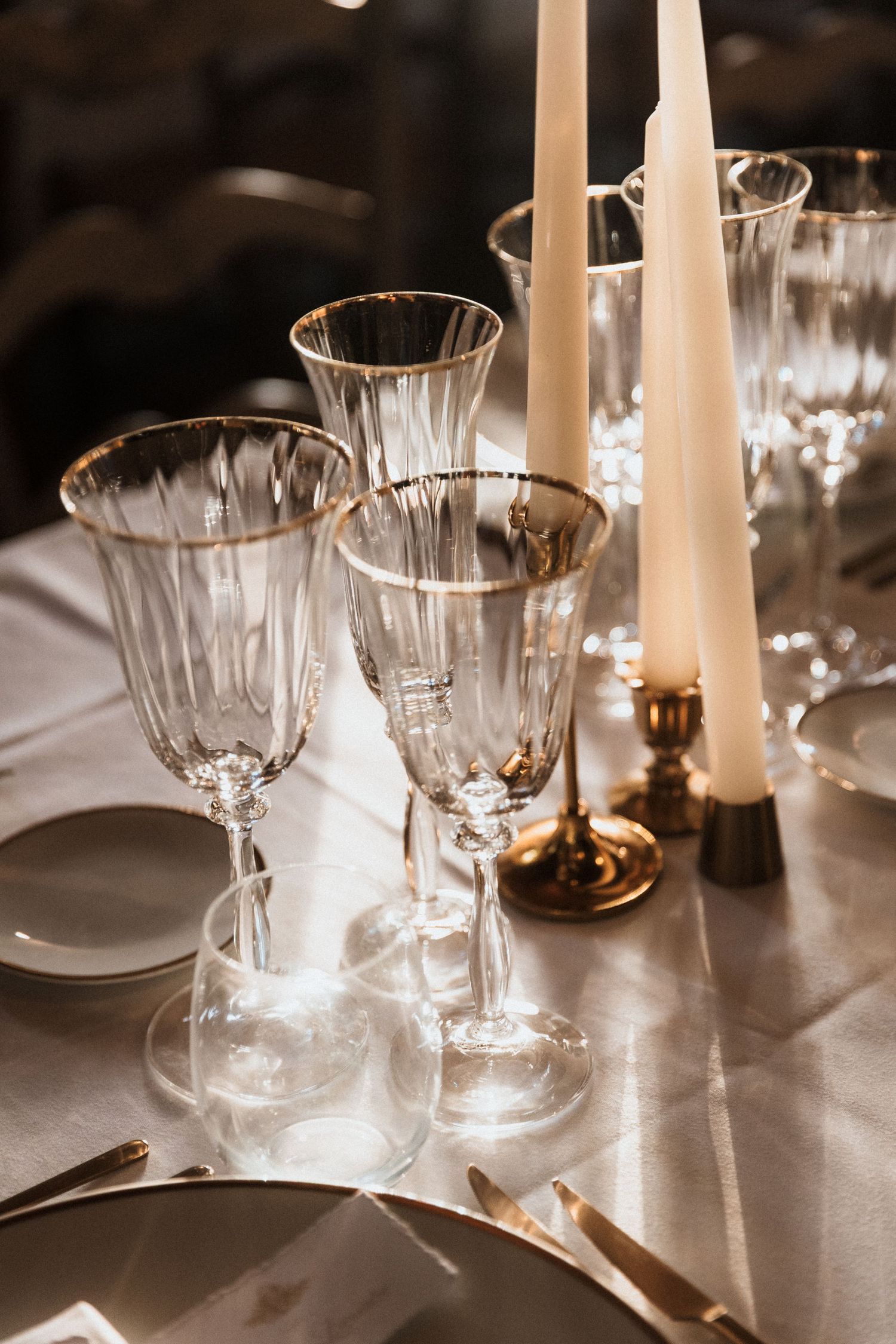 Elegant table setting with crystal glasses and white candles creating a romantic dining atmosphere.