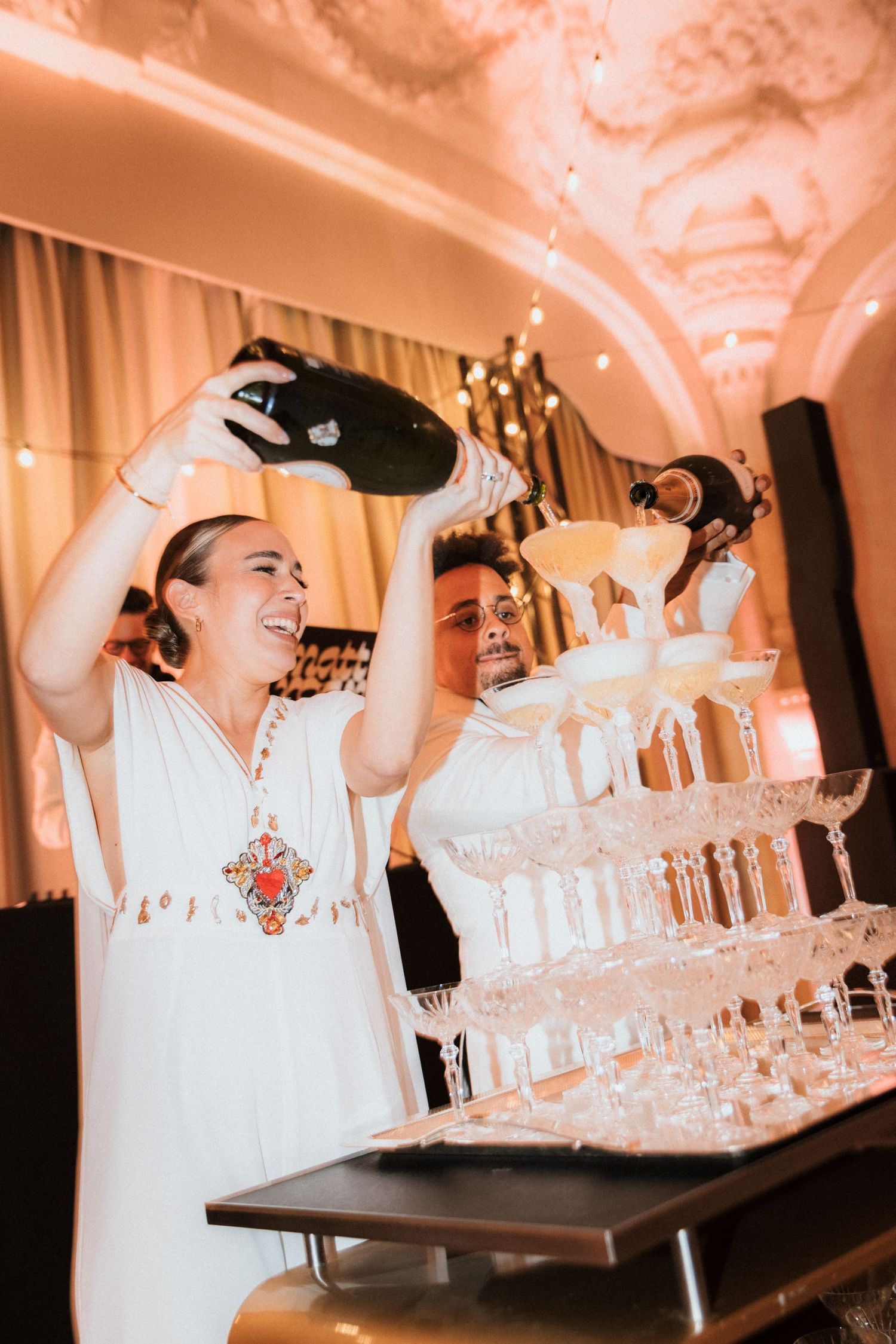 Pouring champagne into tower of glasses at elegant reception.