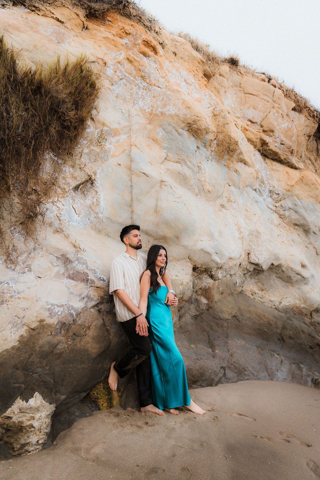 Editorial Laguna Beach engagement: Couple posing against golden cliffs. Cinematic destination session by Raw Studio in Southern California