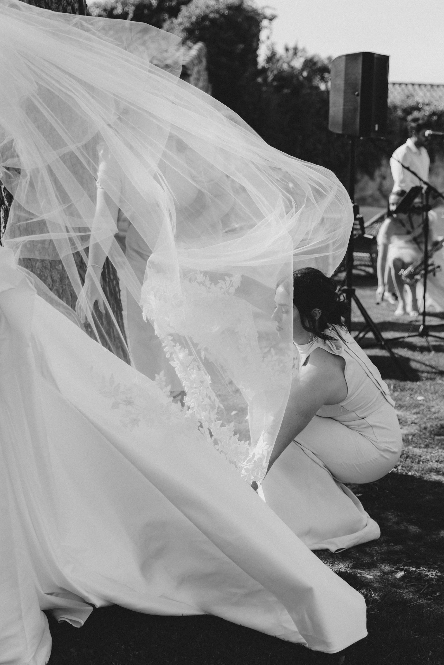 Black and white photo of a flowing wedding dress veil caught in the wind during an outdoor photoshoot.