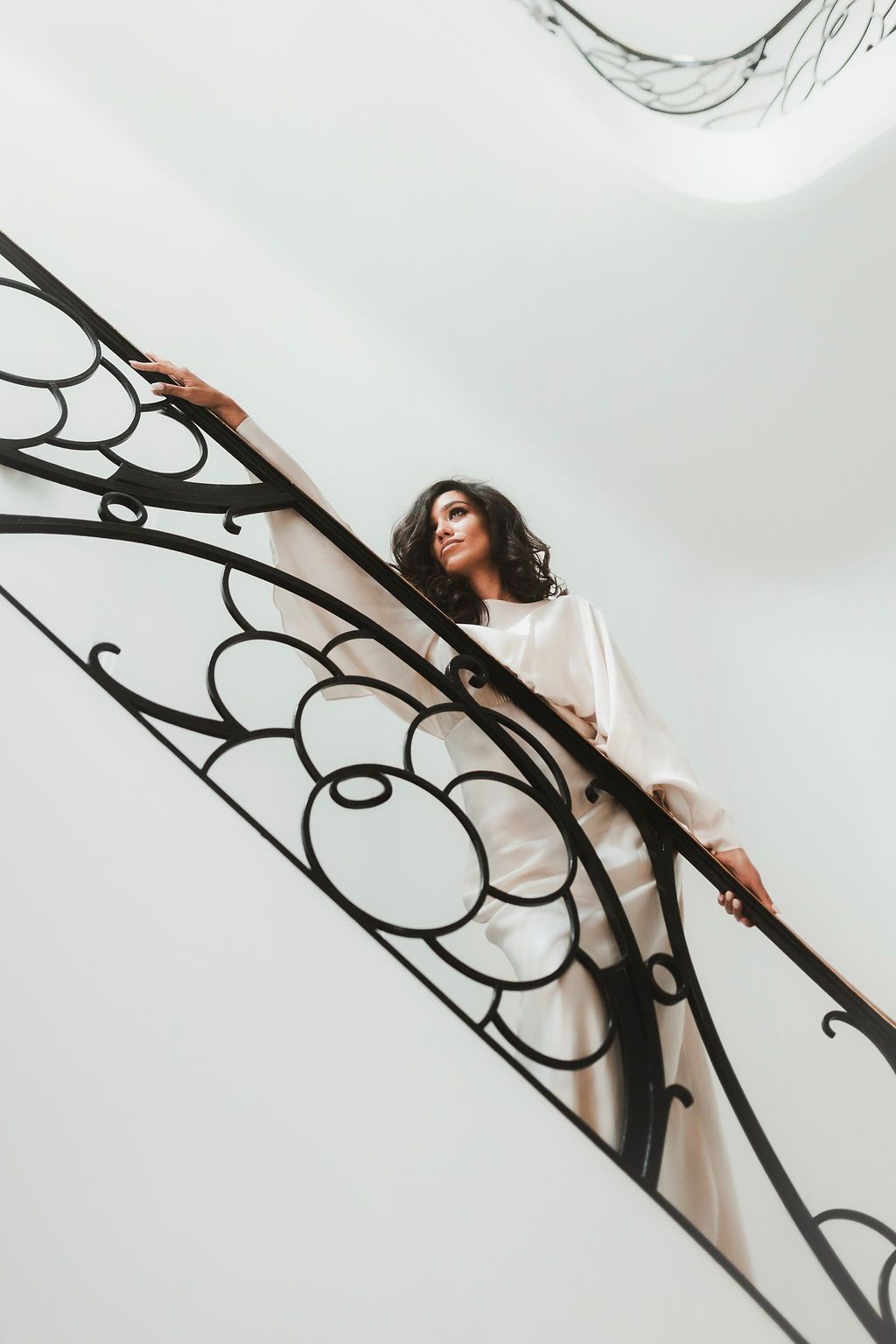 Artistic wedding portrait featuring ornate iron railings and soft natural lighting.