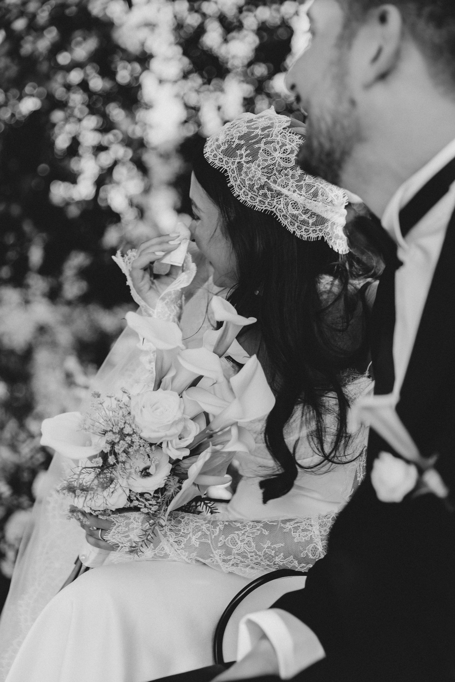 Black and white close-up of wedding bouquet with white flowers and delicate lace details.