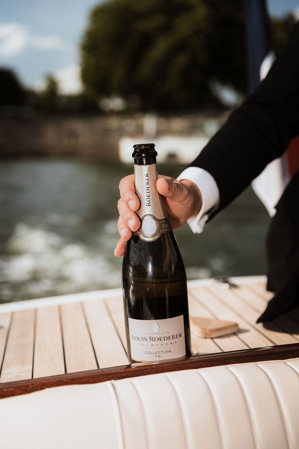 Louis Roederer champagne on the wooden deck of Le Bateau Français. Luxury elopement styling for a bespoke Paris boat wedding.