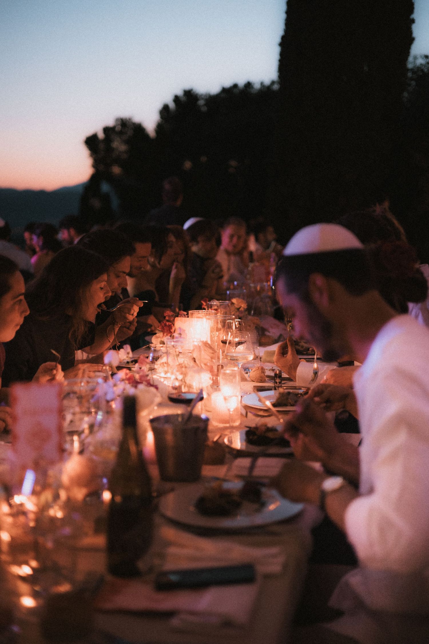 Candlelit wedding reception tables creating a romantic ambiance at dusk.