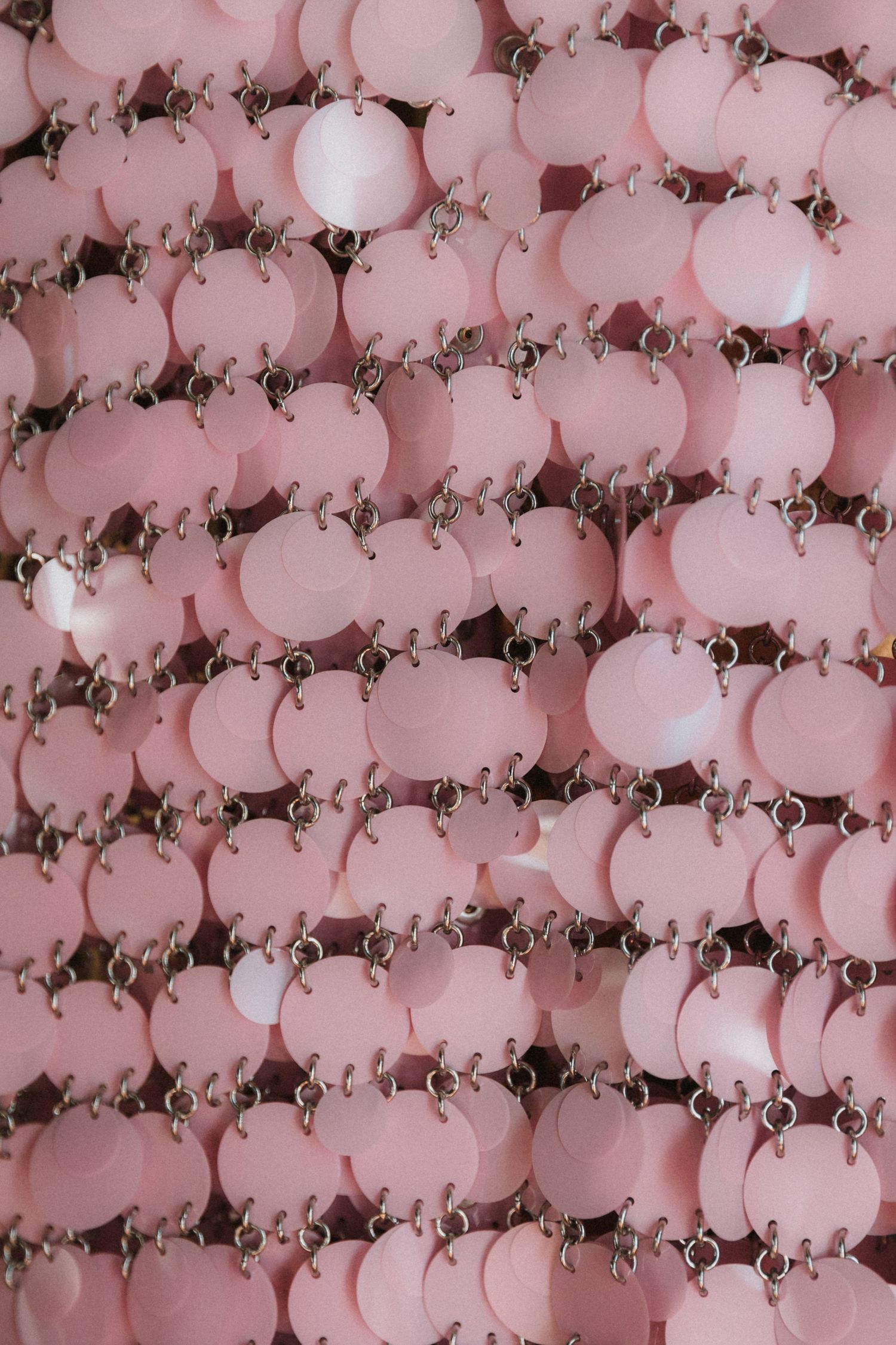 Pattern of pink and white circular beads arranged in rows creating a retro decorative background texture.