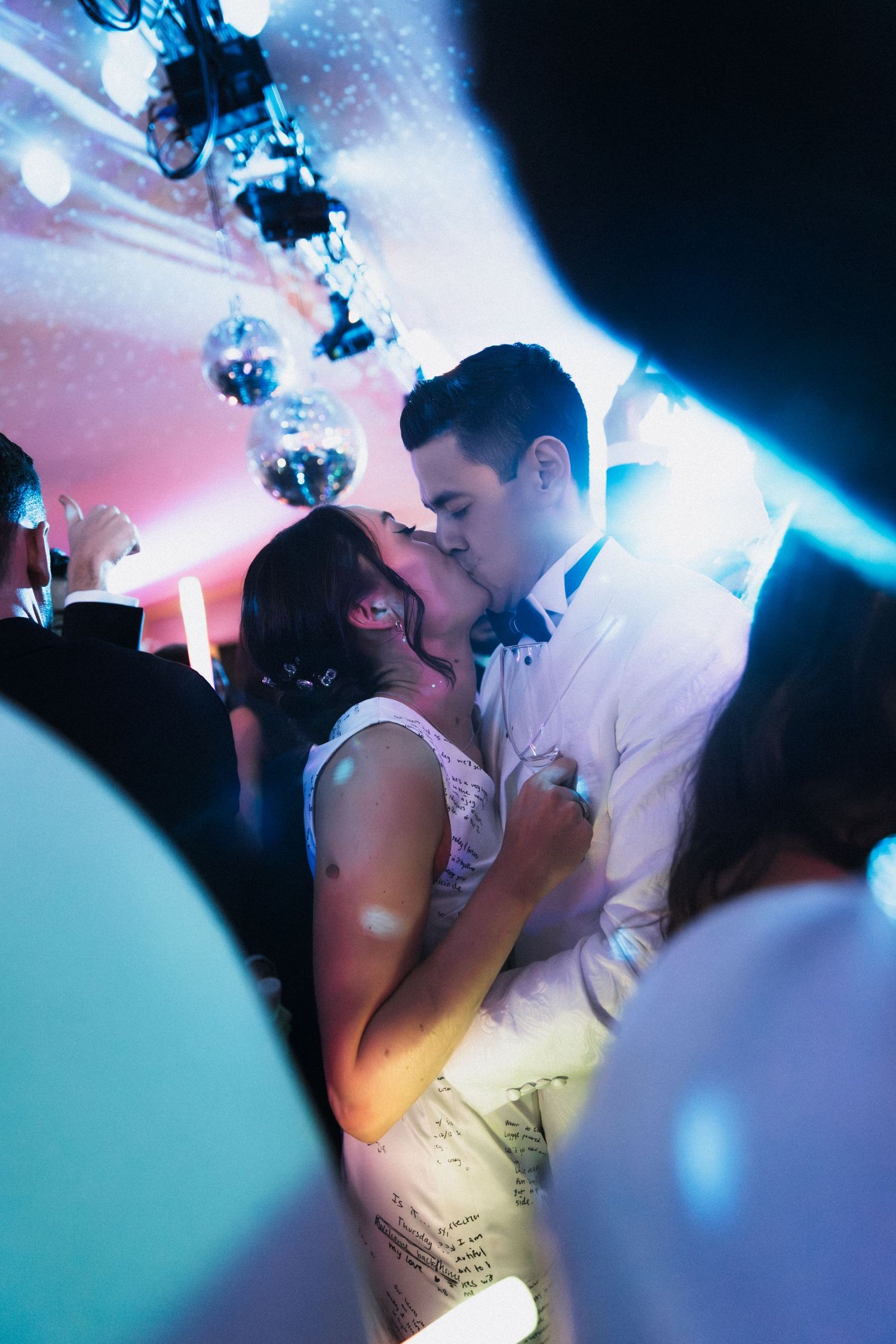 Dance floor scene at a wedding reception with disco lights and dancing silhouettes.