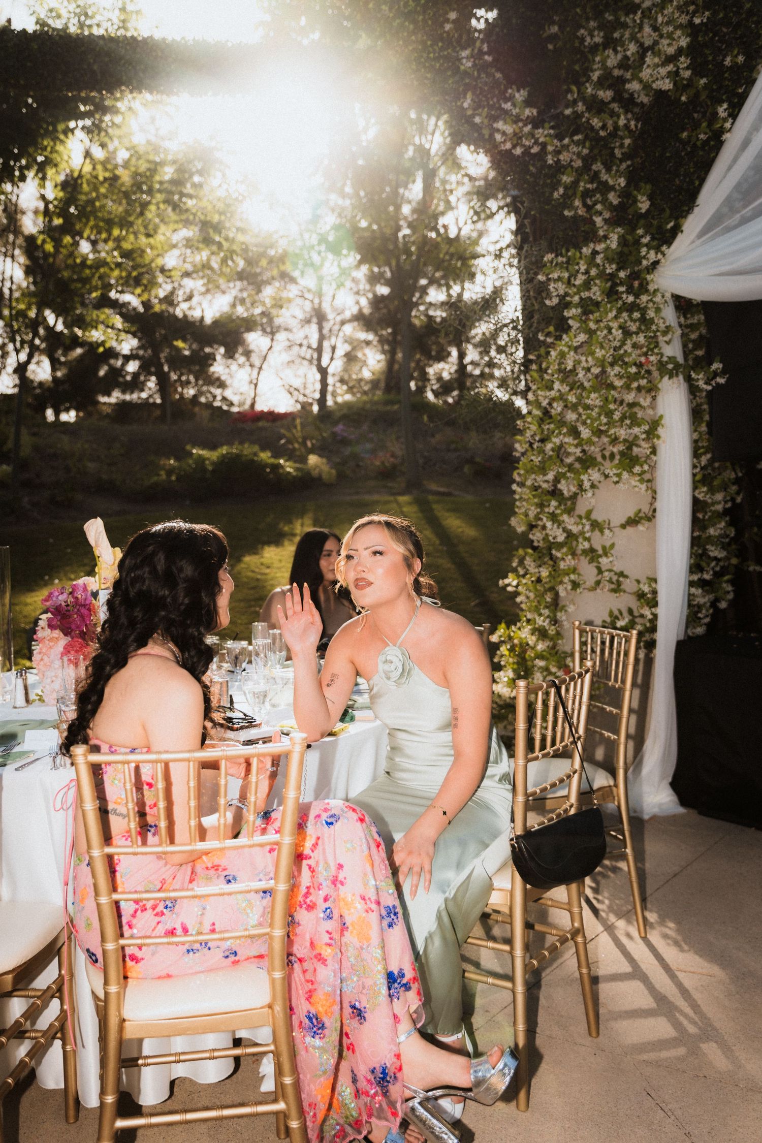 Wedding guests sharing a fun moment at an outdoor reception table during sunset.