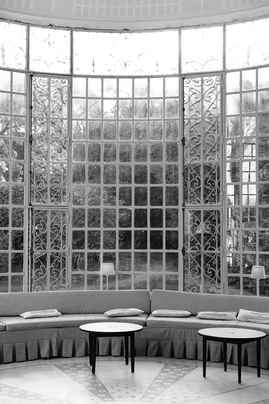 Elegant curved conservatory interior with ornate ironwork windows and built-in bench seating along the perimeter.