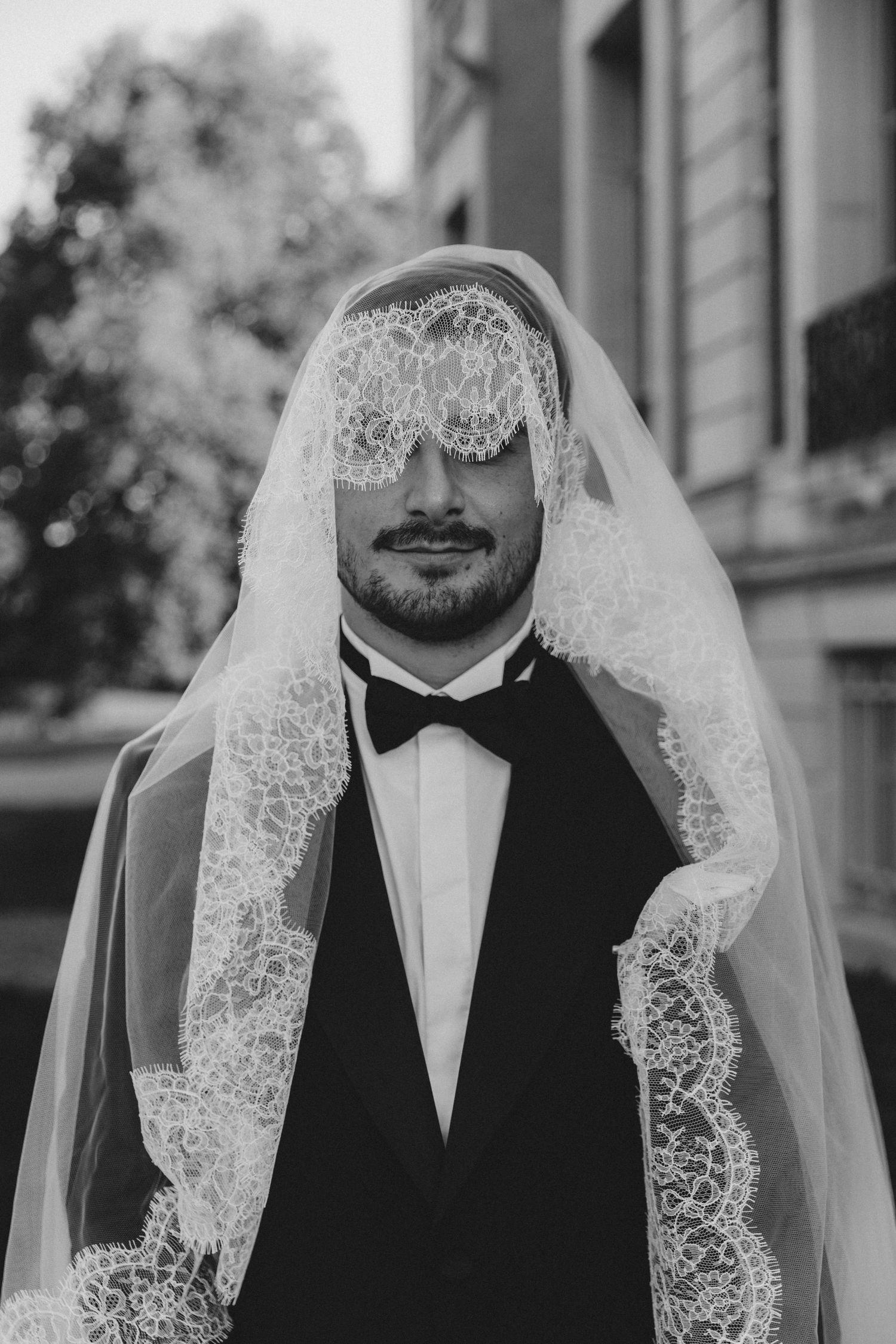 A black and white close-up photo of someone wearing a bridal veil and formal attire.