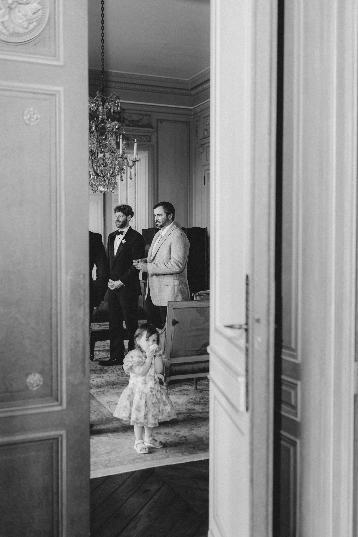 Series of black and white photos showing wedding party walking through elegant hallway with mirrored walls.