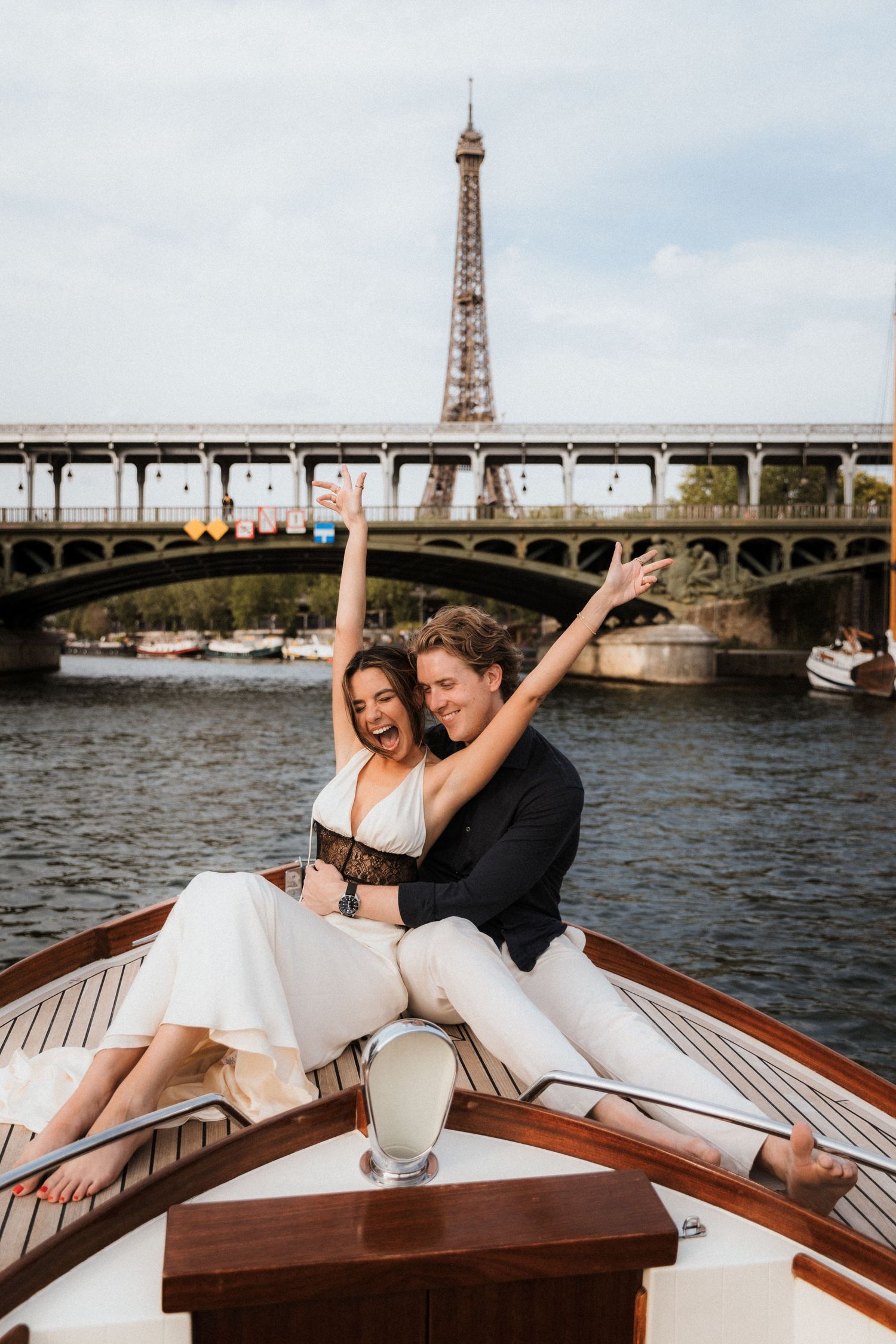 Joyful couple celebrating on a boat on the Seine River with the Eiffel Tower in Paris, France.