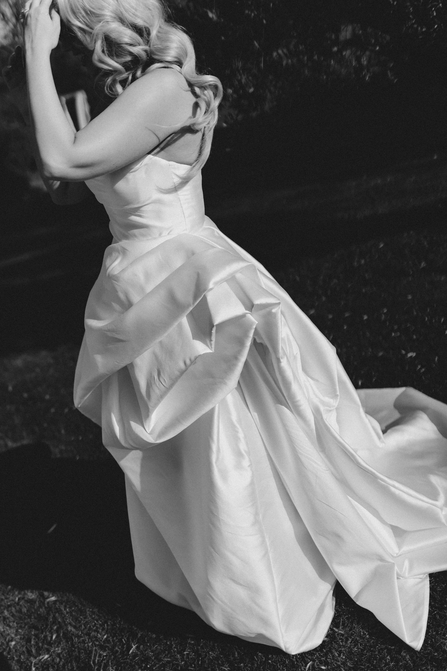 A flowing white wedding dress swirls gracefully in a black and white artistic photo series.