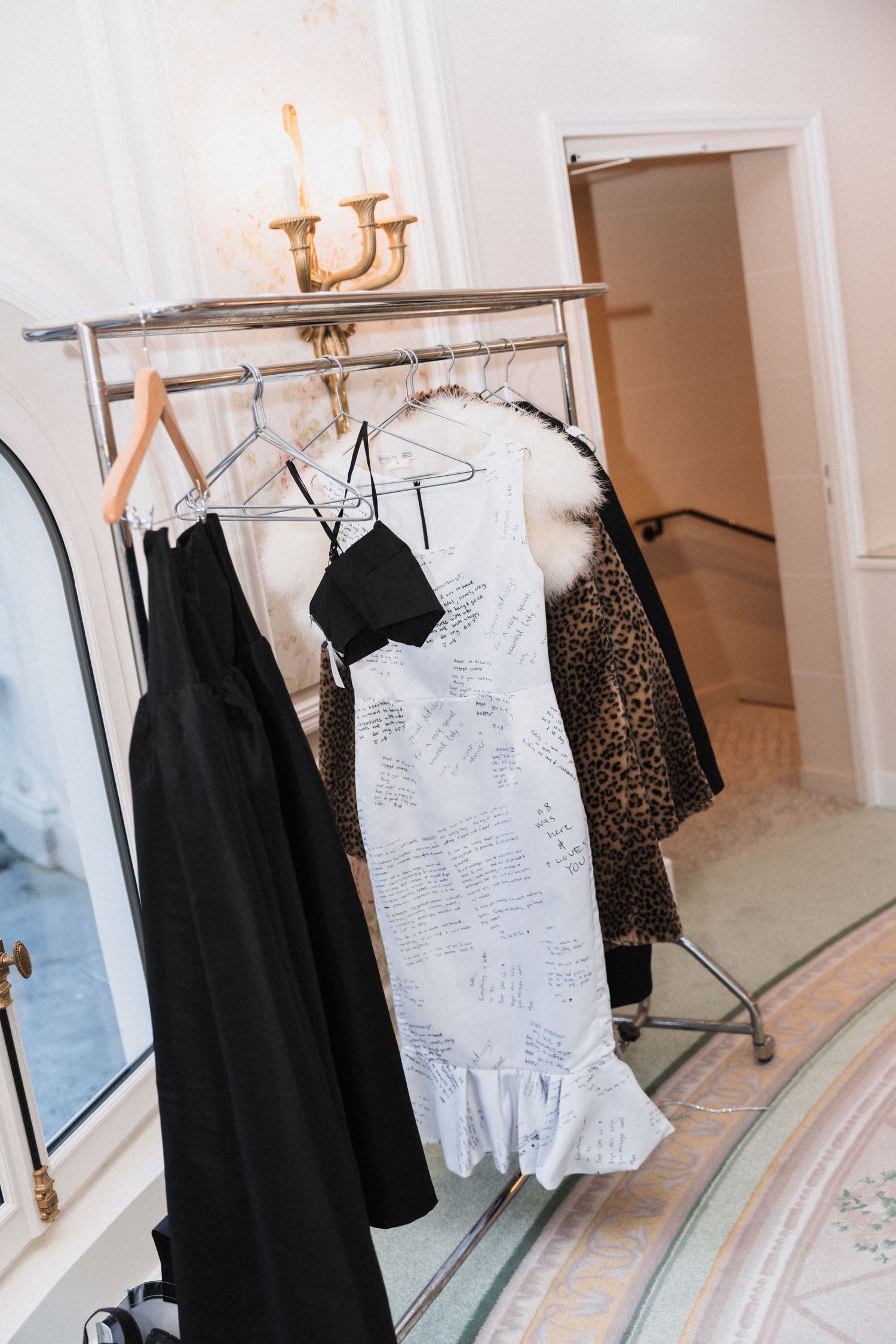 Wedding dresses and formal attire displayed on clothing racks in an elegant boutique setting.