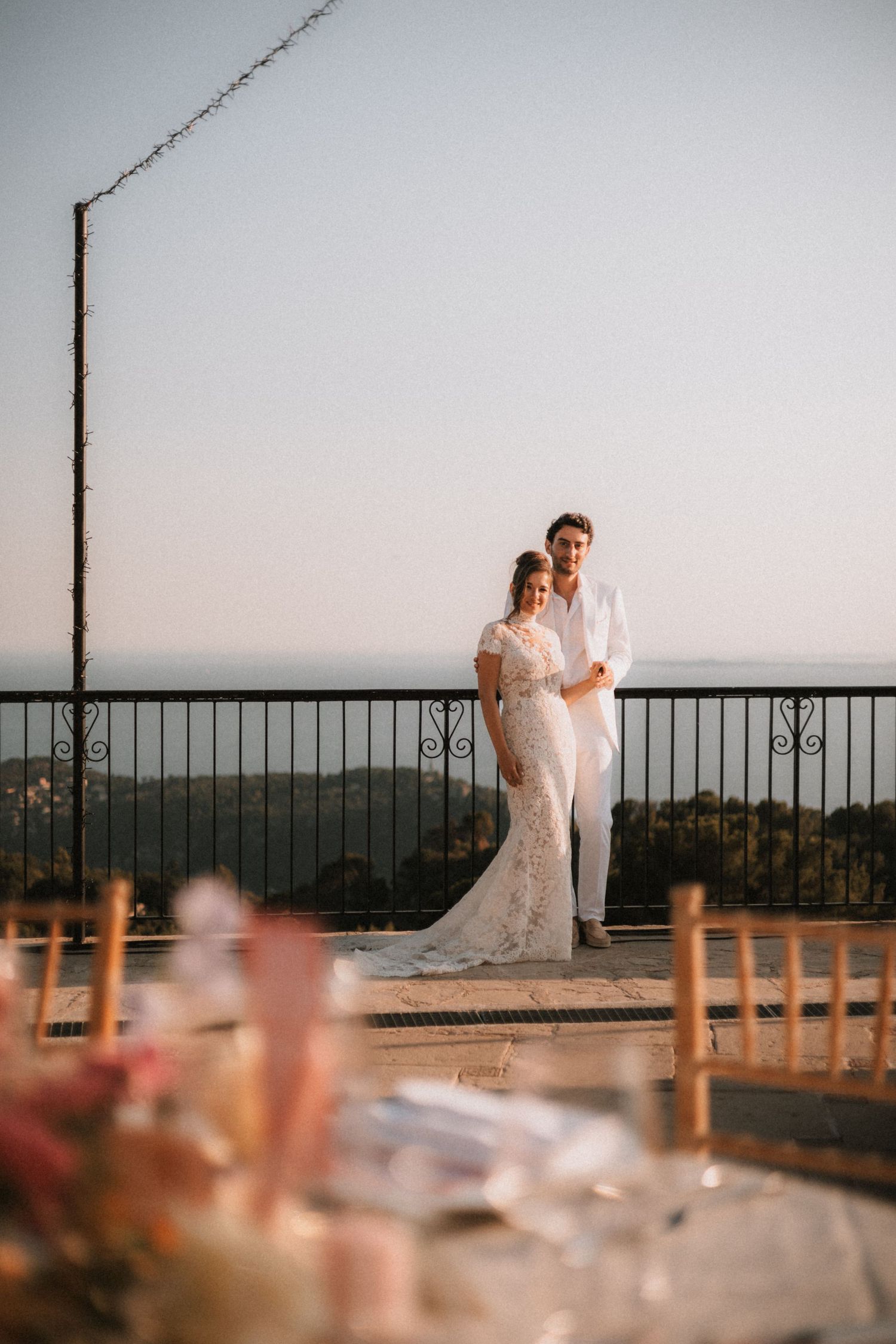 Wedding couple posing on terrace with scenic mountain vista in background.