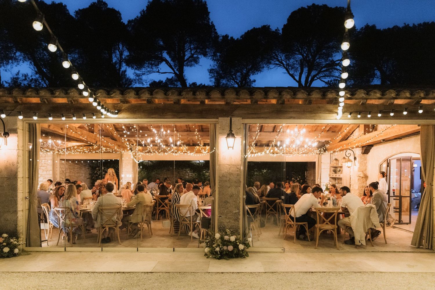 Evening outdoor wedding venue illuminated with string lights and lanterns.