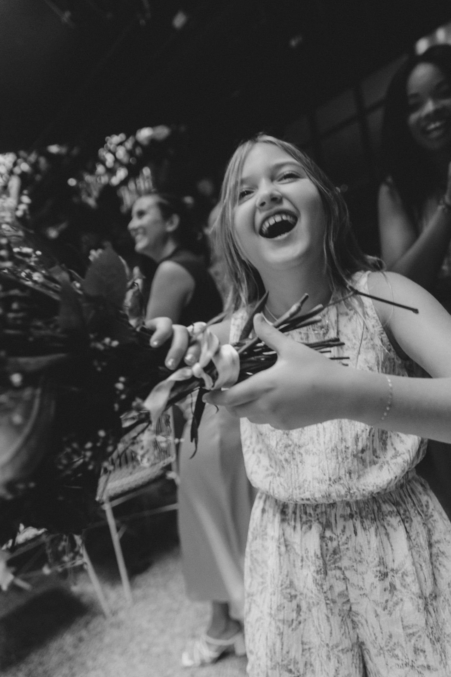 A series of black and white photos showing someone in a white dress laughing and playing with confetti outdoors.