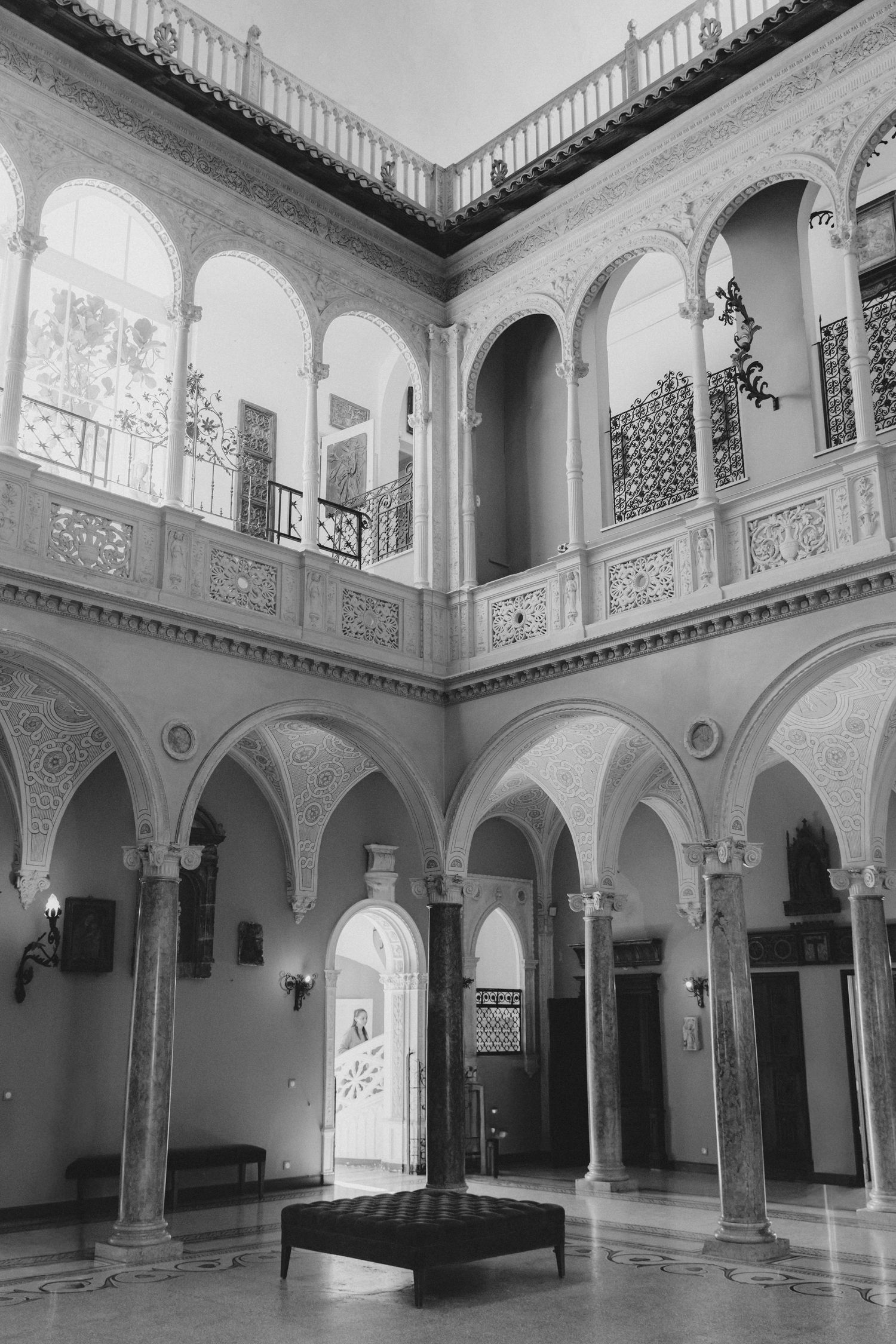Villa Ephrussi - Black and white photo of an elegant courtyard with arched colonnades, ornate details, and a two-story balcony interior.