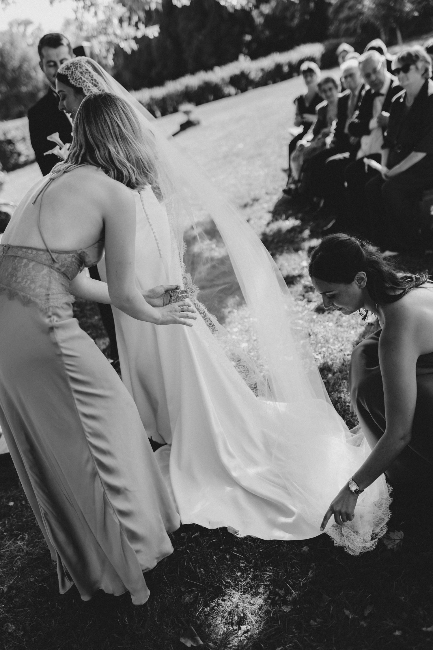 Wedding party members in light colored dresses walking together outdoors.
