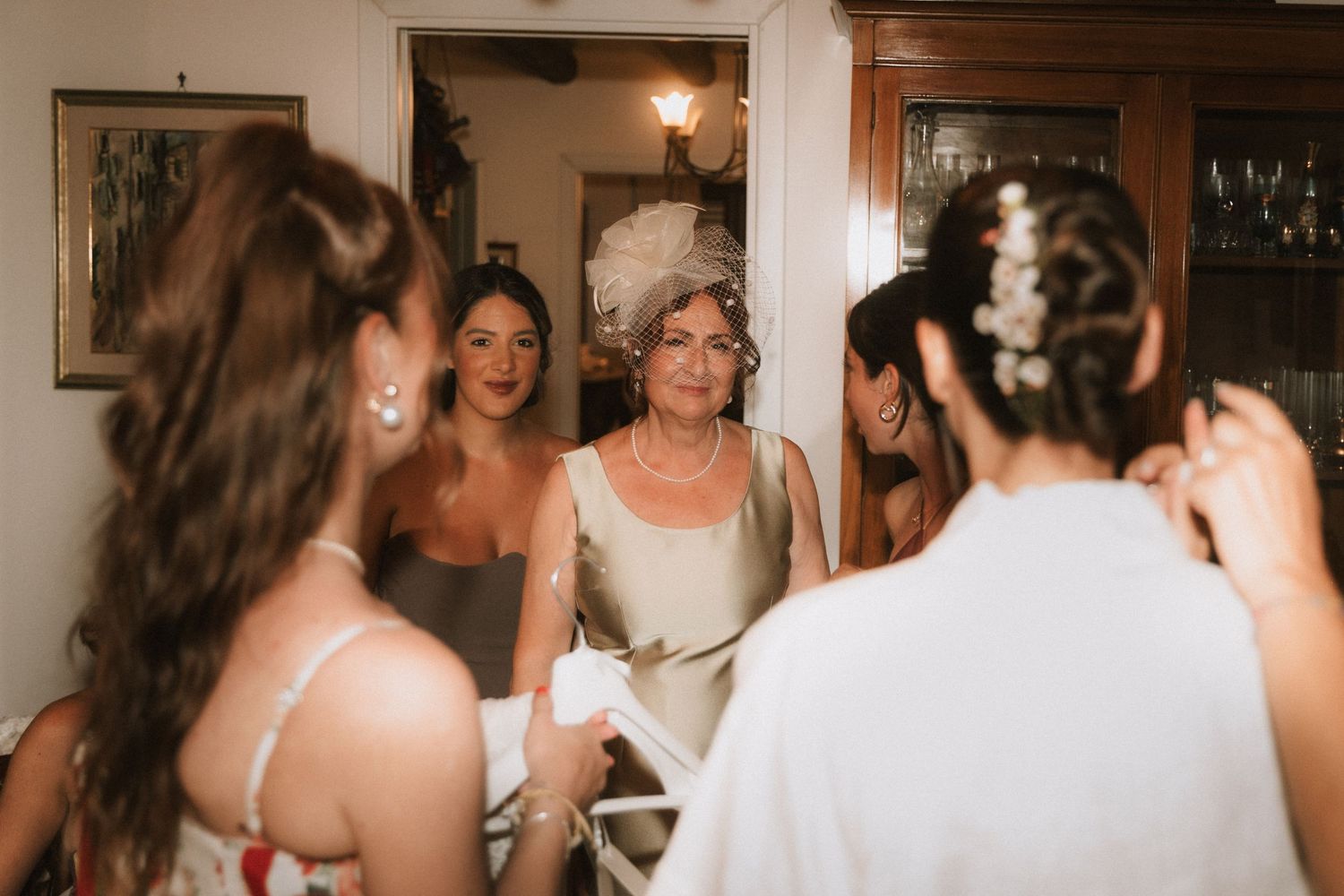 A group of wedding guests dance and celebrate together at a reception in a warmly lit indoor venue.