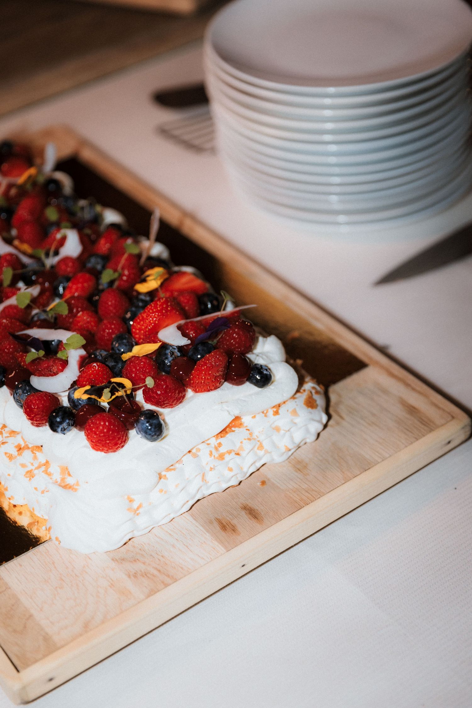 Fresh berries and cream dessert displayed on a wooden serving board.