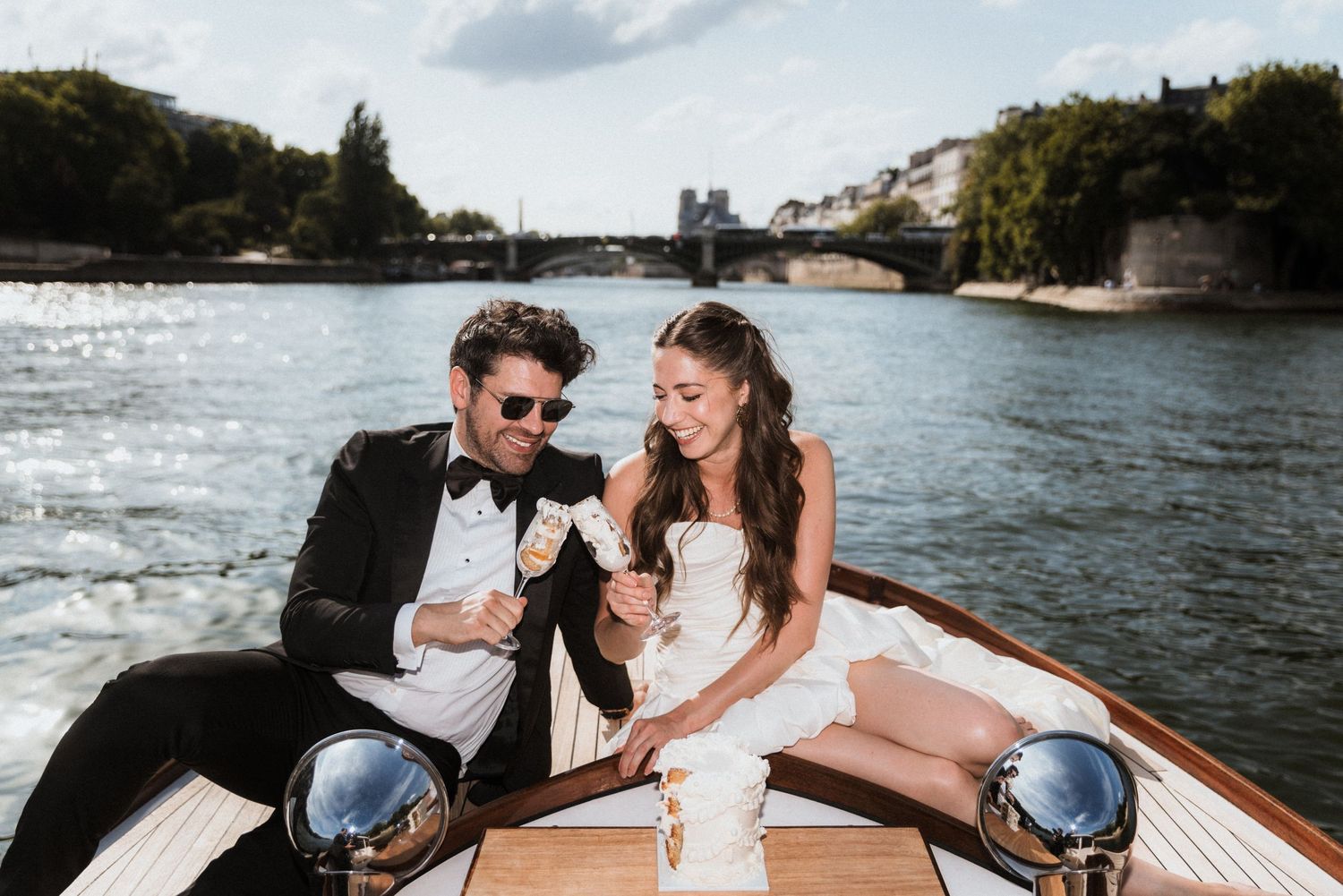 Romantic Paris boat elopement: Couple sharing champagne on Le Bateau Français along the Seine River. Chic, bespoke wedding photography