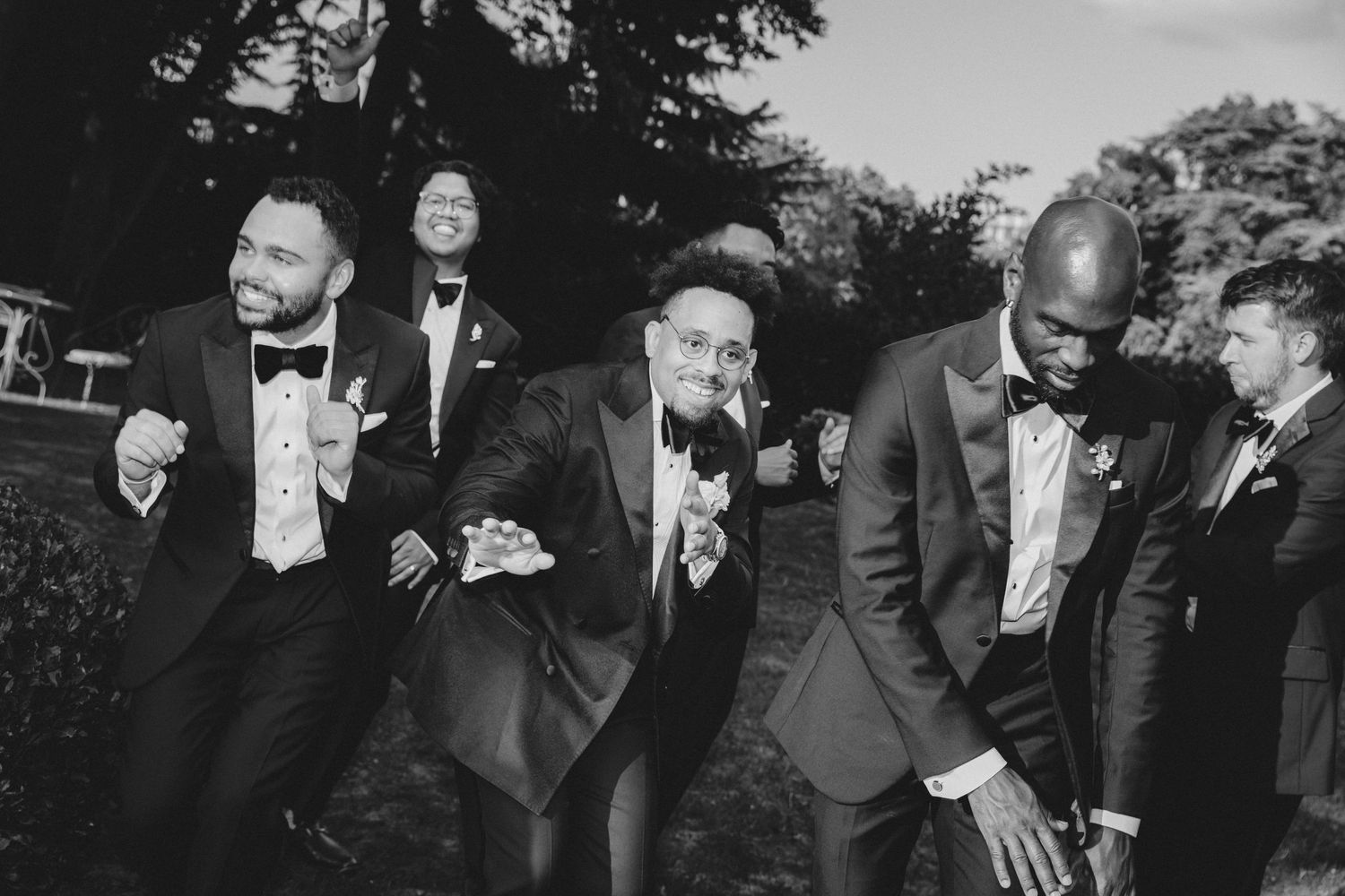 Black and white photo of wedding guests laughing and celebrating during an outdoor reception.