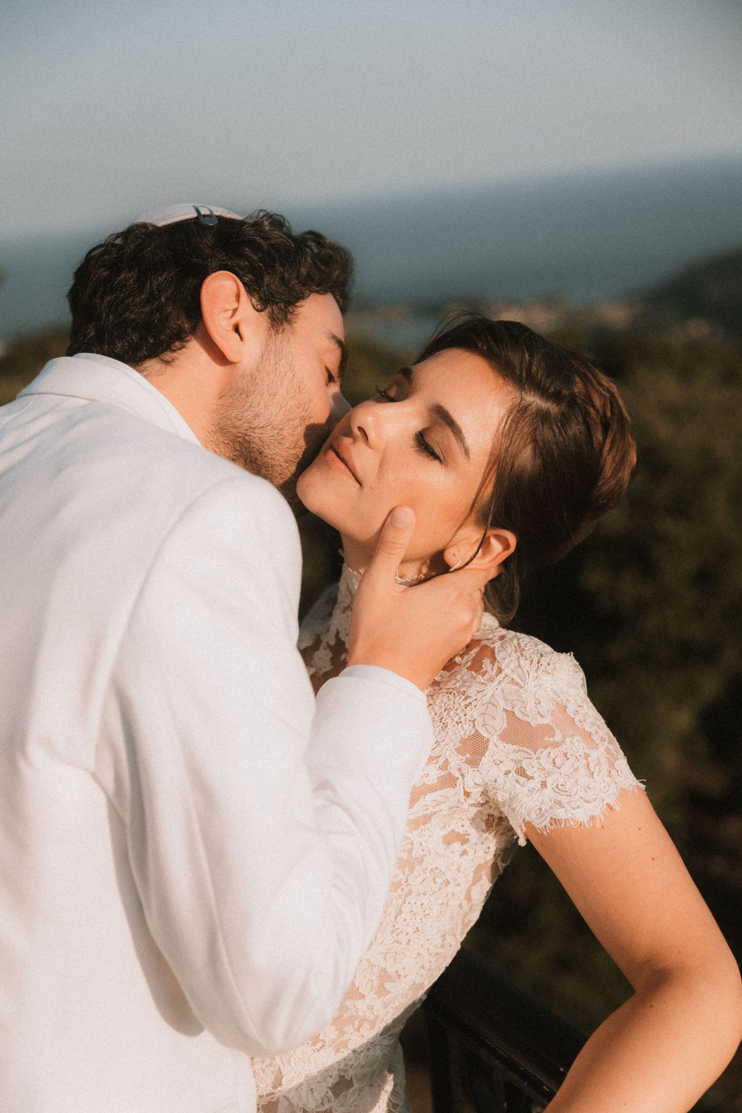 Intimate wedding couple moment captured during golden hour on a scenic overlook.