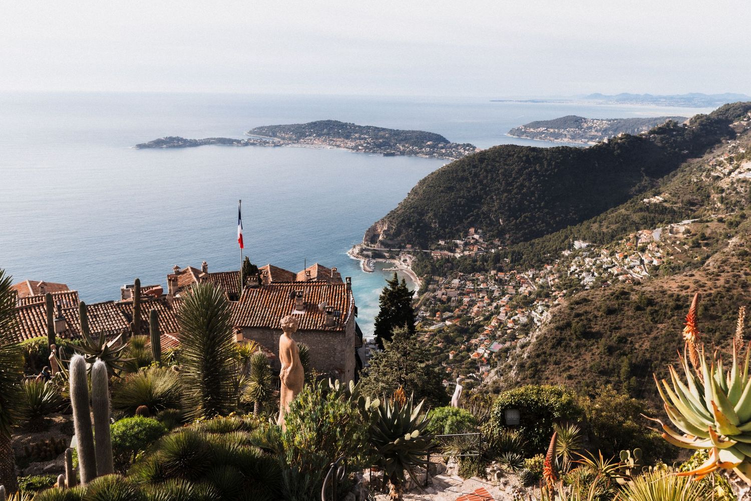 Château Eza - Panoramic view of Eze village with terracotta rooftops, exotic cacti, and the azure Mediterranean Sea coastline in France.