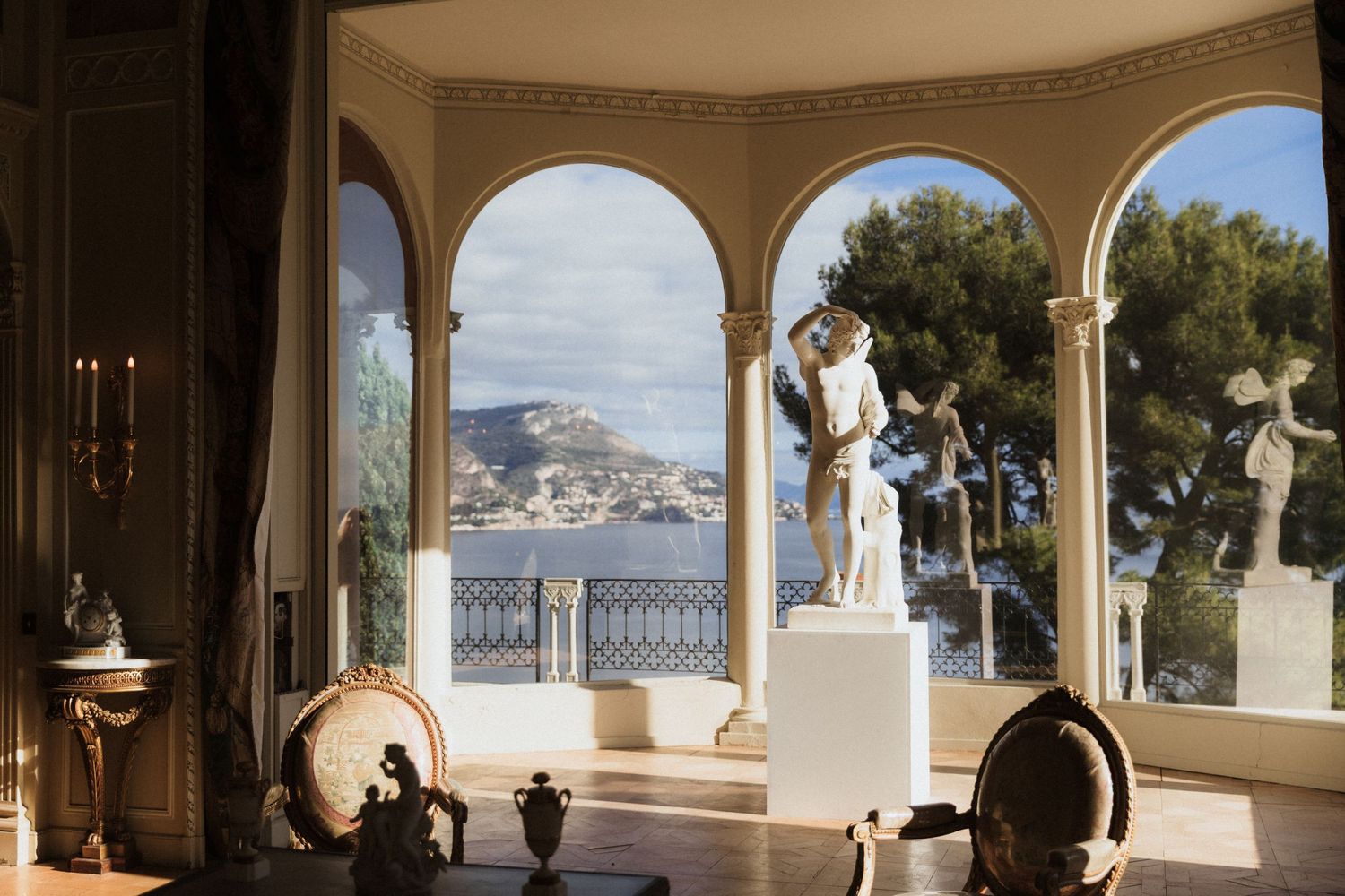 Villa Ephrussi de Rothschild - Elegant villa loggia with arched columns, classical statue, and stunning Mediterranean coastal view.