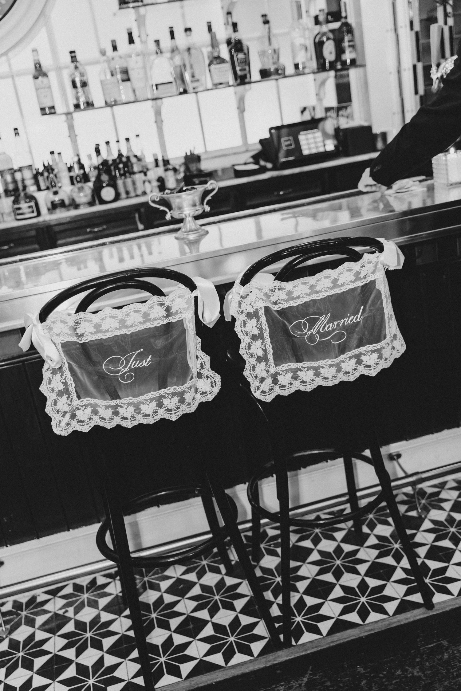 Black and white photo of two bar stools with Just Married signs at a wedding venue bar.