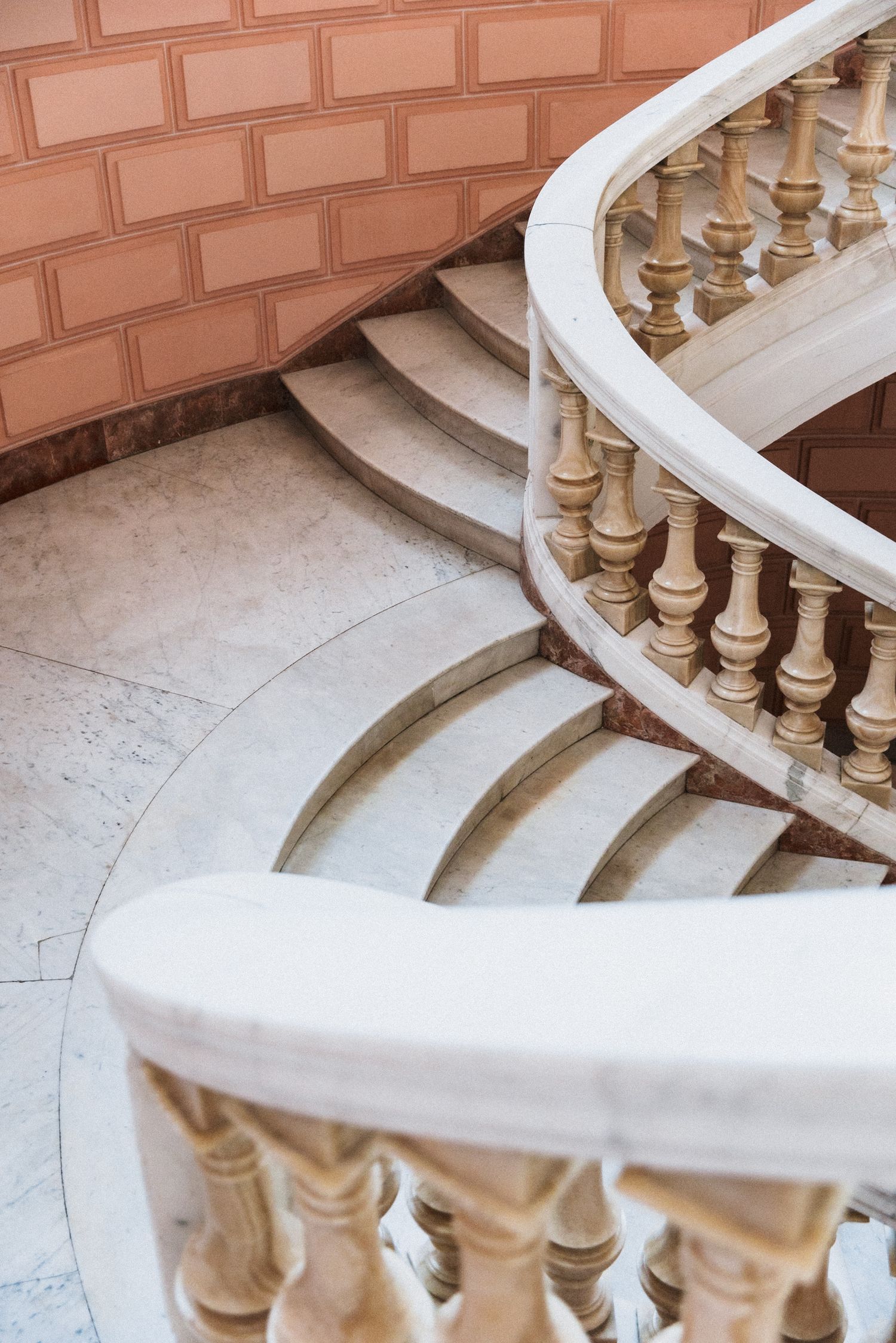 Villa Rocabella - Elegant curved marble staircase with ornate wooden balusters and white handrail in a classic architectural interior.