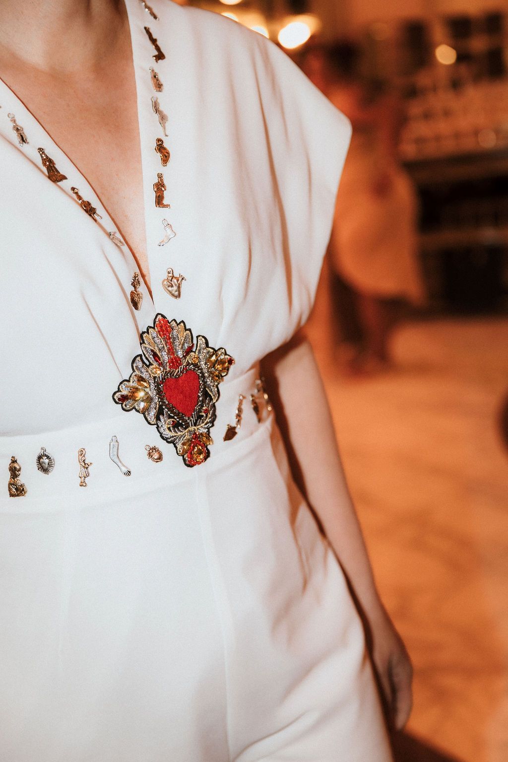 White dress with ornate red heart embellishment and decorative beading detail.