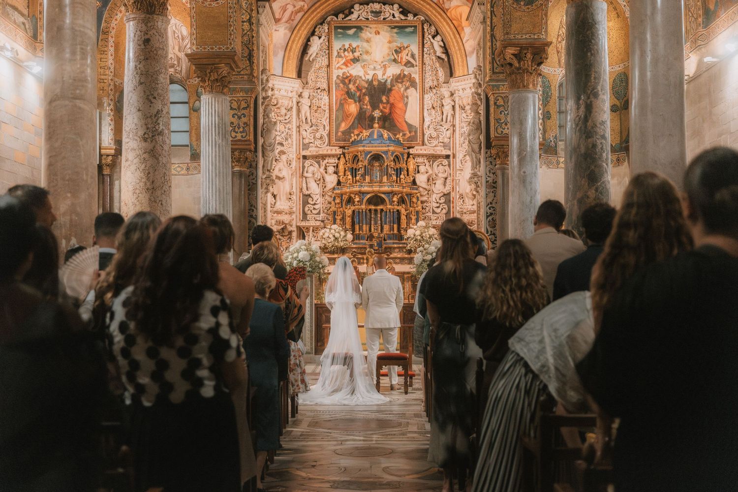 Interior of an ornate cathedral during a wedding ceremony with guests seated in pews.