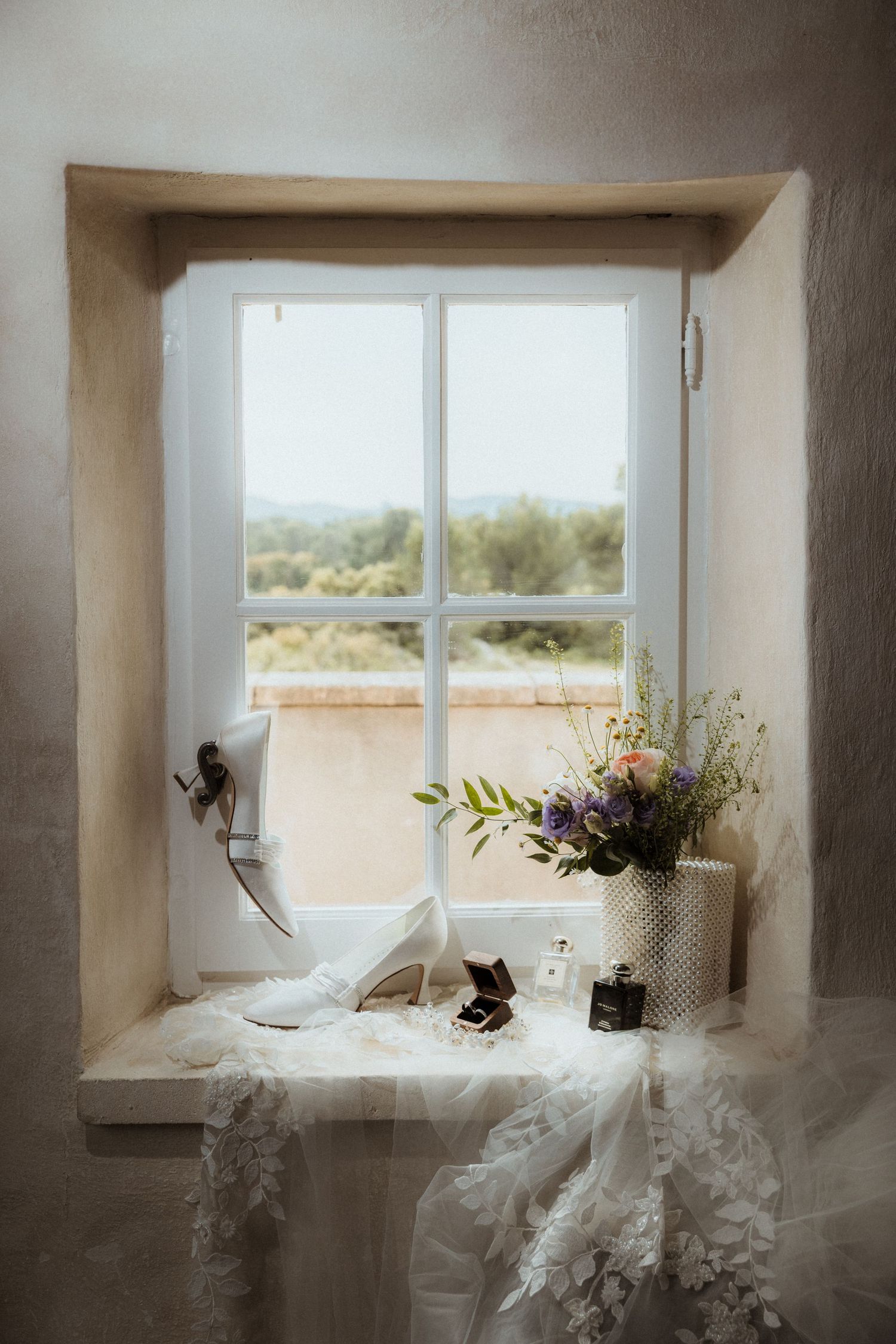 Delicate white tulle and floral arrangements displayed near sunlit windows in rustic interior.