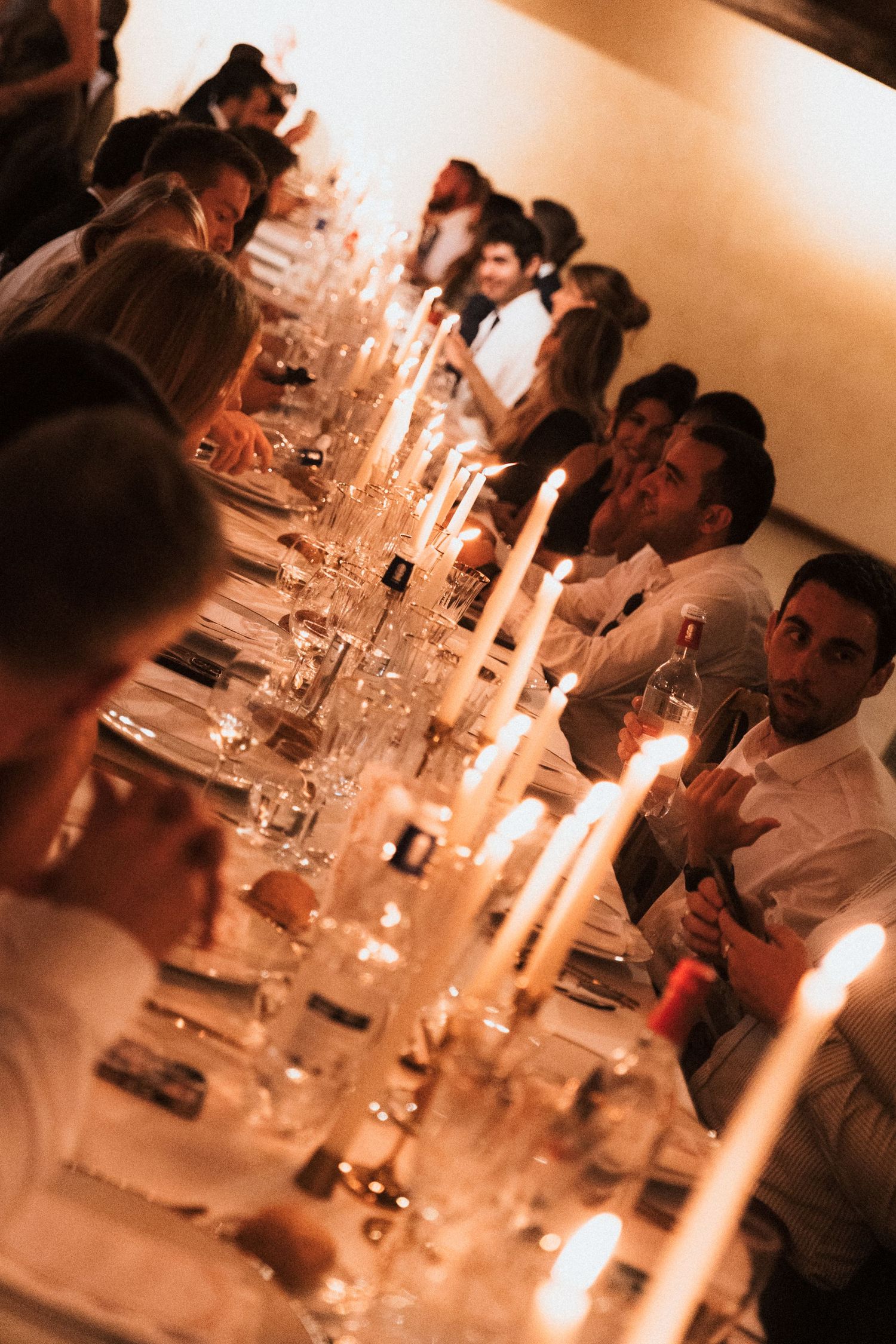 Elegant dinner table setting with glowing candles creating a warm ambiance during an evening gathering.