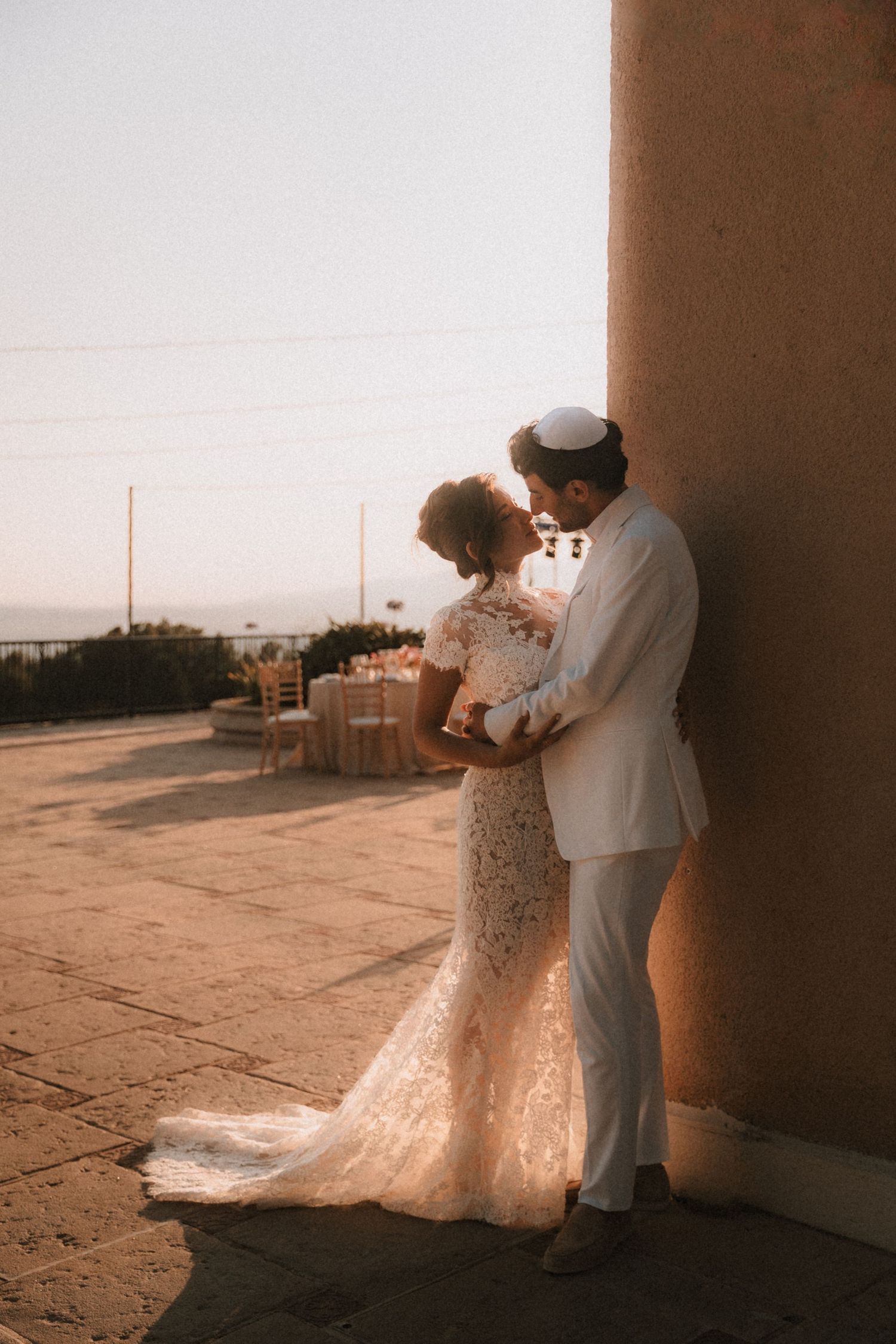 Romantic silhouettes of a couple in wedding attire dancing against a sunset backdrop.