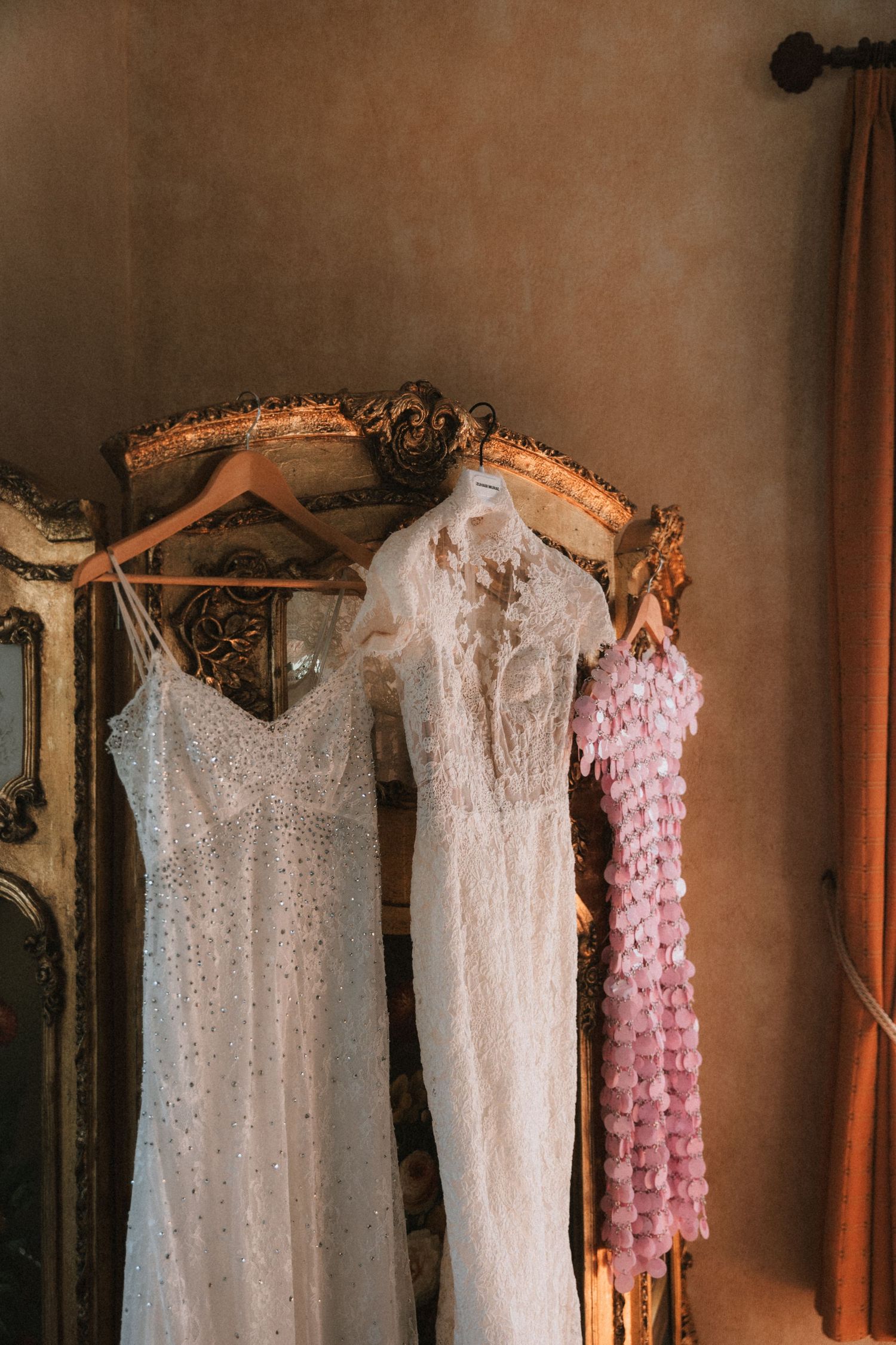 Elegant wedding dresses hanging in a row displaying intricate lace and beaded details.