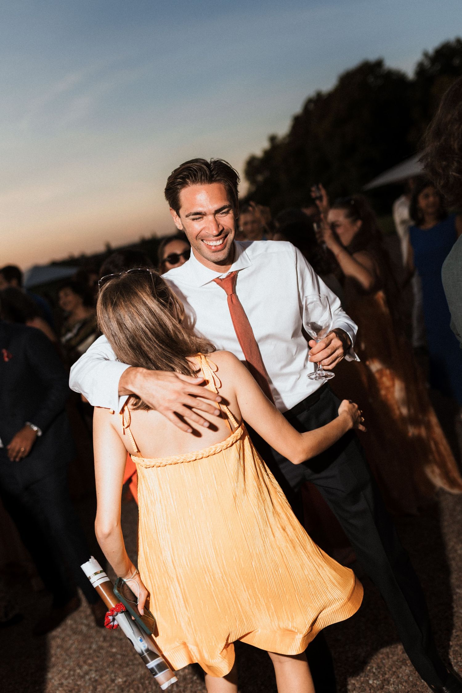Couples dancing and celebrating at an outdoor sunset wedding reception.