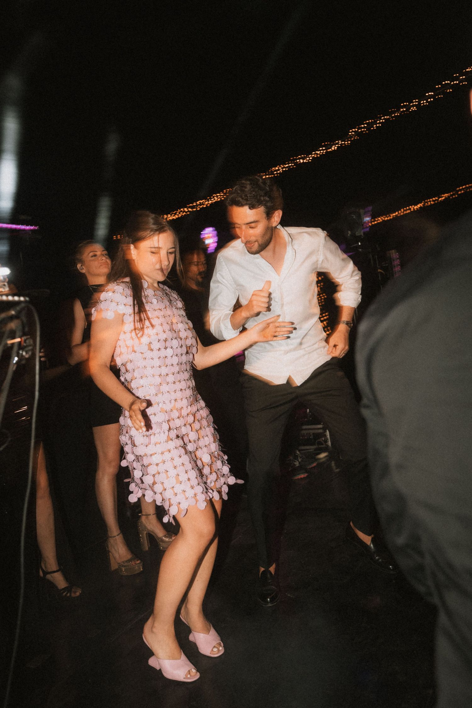 Dancing couple spins on dark dance floor during wedding reception celebration.