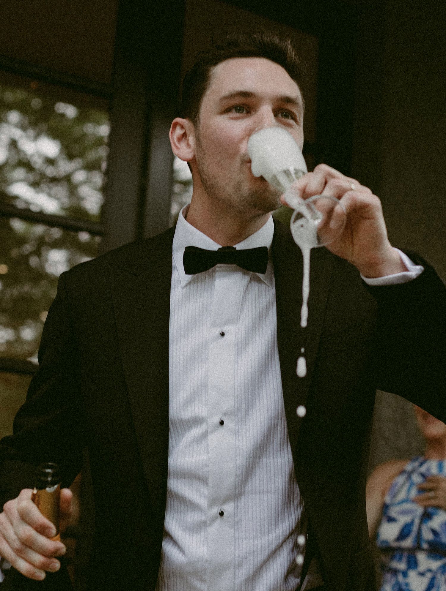 Groom drinking from an overflowing champagne glass at his Muskoka wedding.