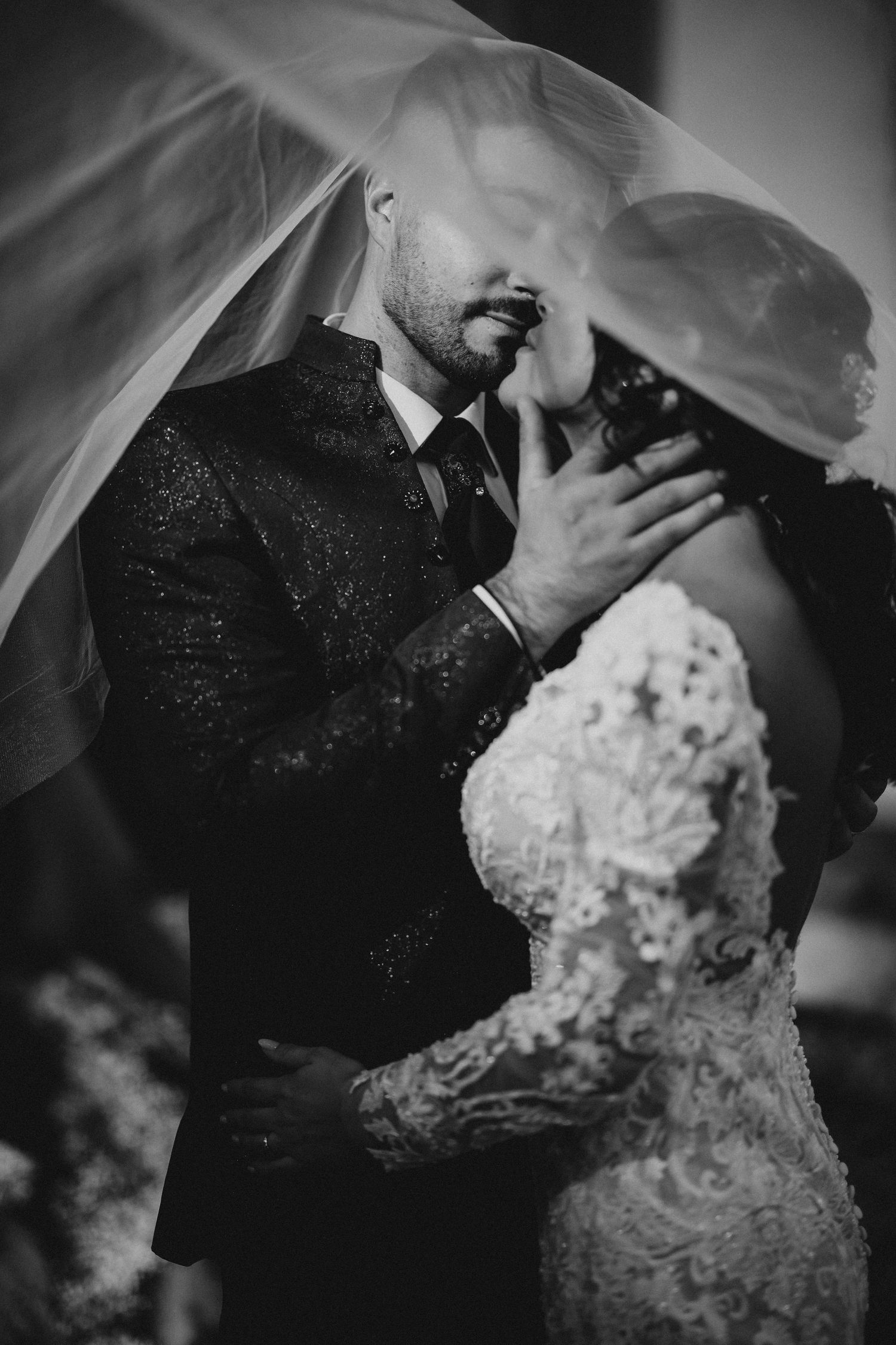 A romantic black and white wedding photo showing a tender moment between newlyweds under a flowing veil. Wedding in Villa Retiro.