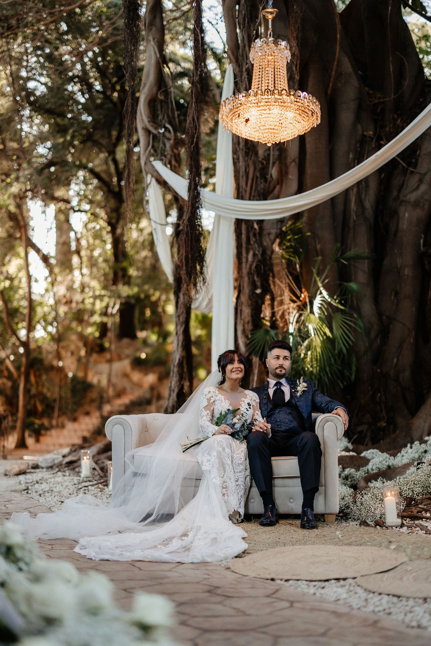 Elegant outdoor forest wedding ceremony setup with flowing white drapes, crystal chandeliers and romantic floral arrangements. Villa retiro.