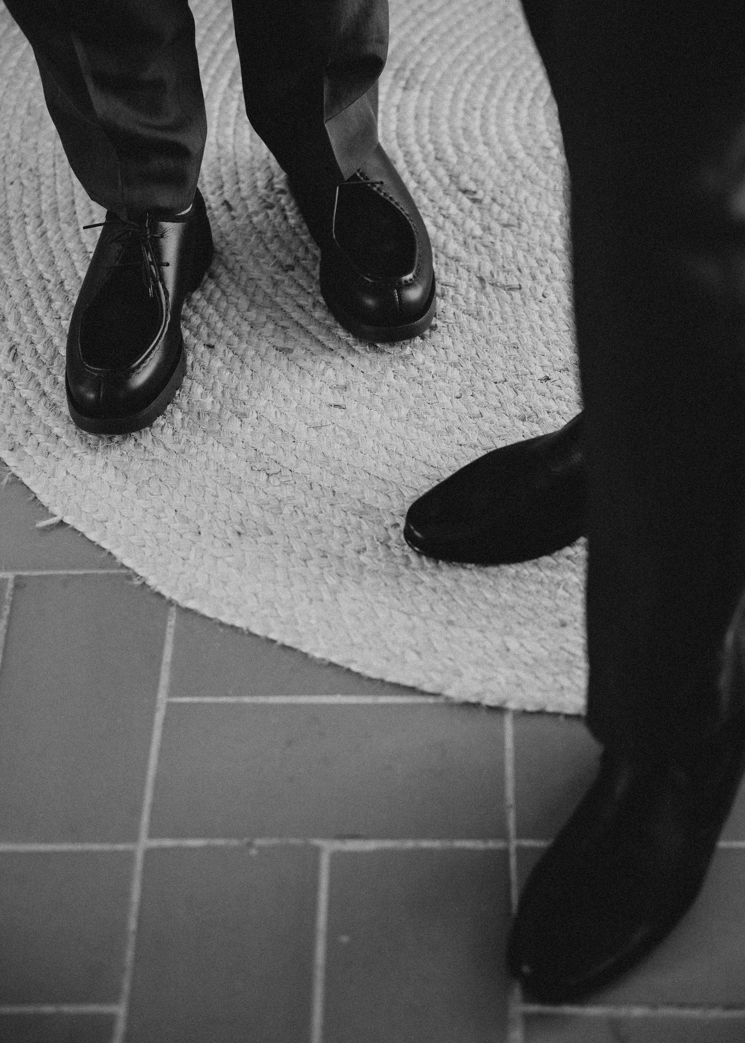 Black and white image of dress shoes walking on a textured carpet or rug surface. Wedding in Mas de l'Illa.