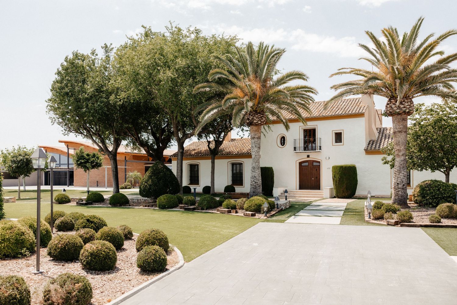 A panoramic view of a Mediterranean-style residential neighborhood with palm trees and white stucco buildings. Wedding in Masia Les Casotes.